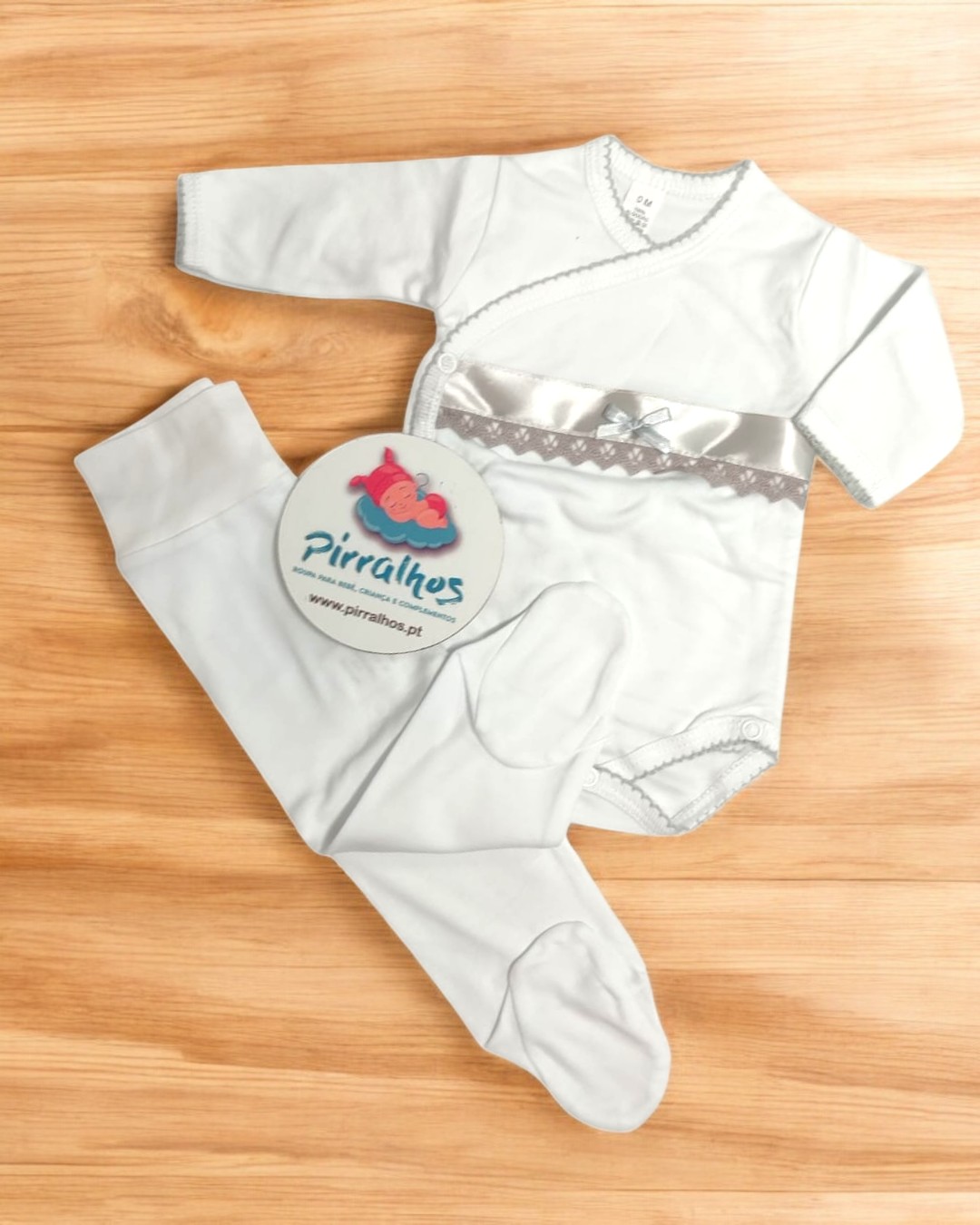 Conjunto de roupa para bebé branco com detalhes cinza e etiqueta redonda