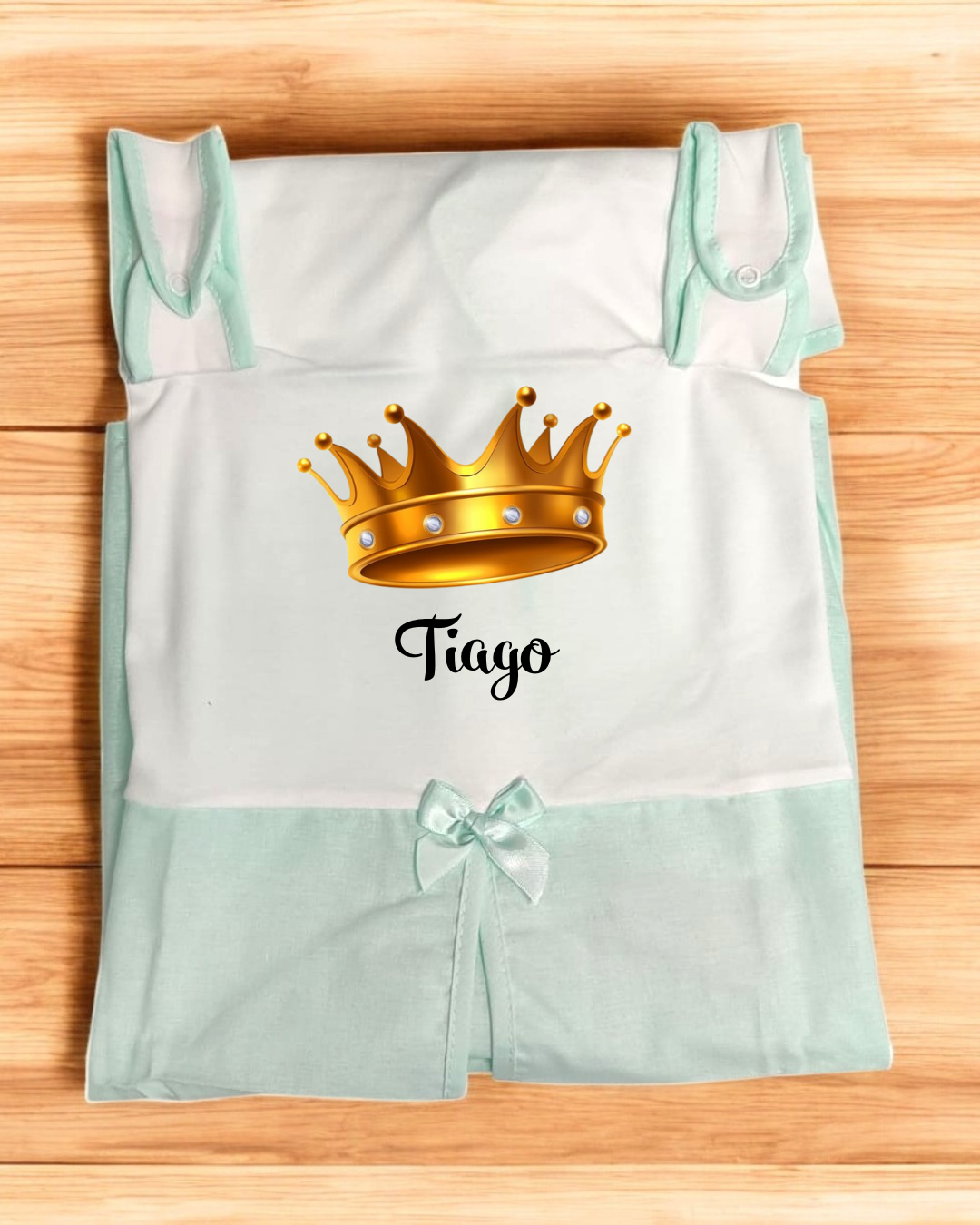 Conjunto de roupa de bebé branco com detalhes verde água e coroa dourada com o nome Tiago.
