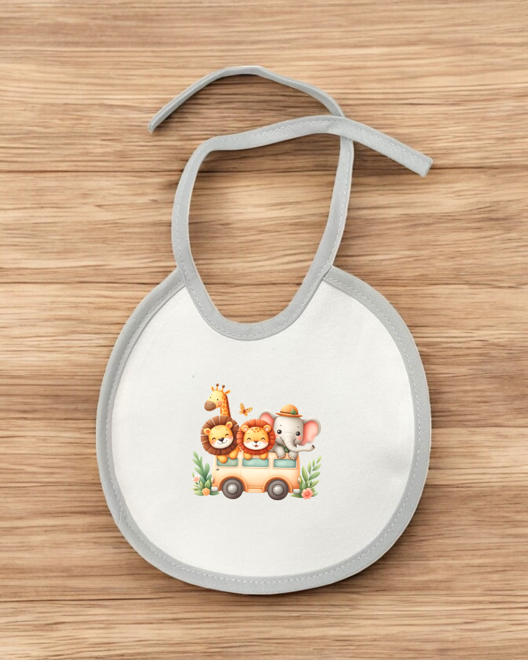 Babete branco com borda cinza e estampa colorida de animais num carrinho sobre madeira