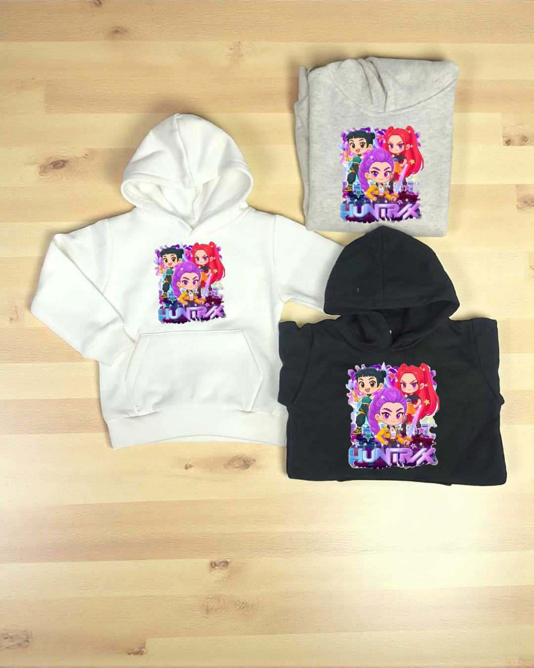 Três sweatshirts coloridas com estampa de personagens de desenho animado e o texto HUNTRIX.