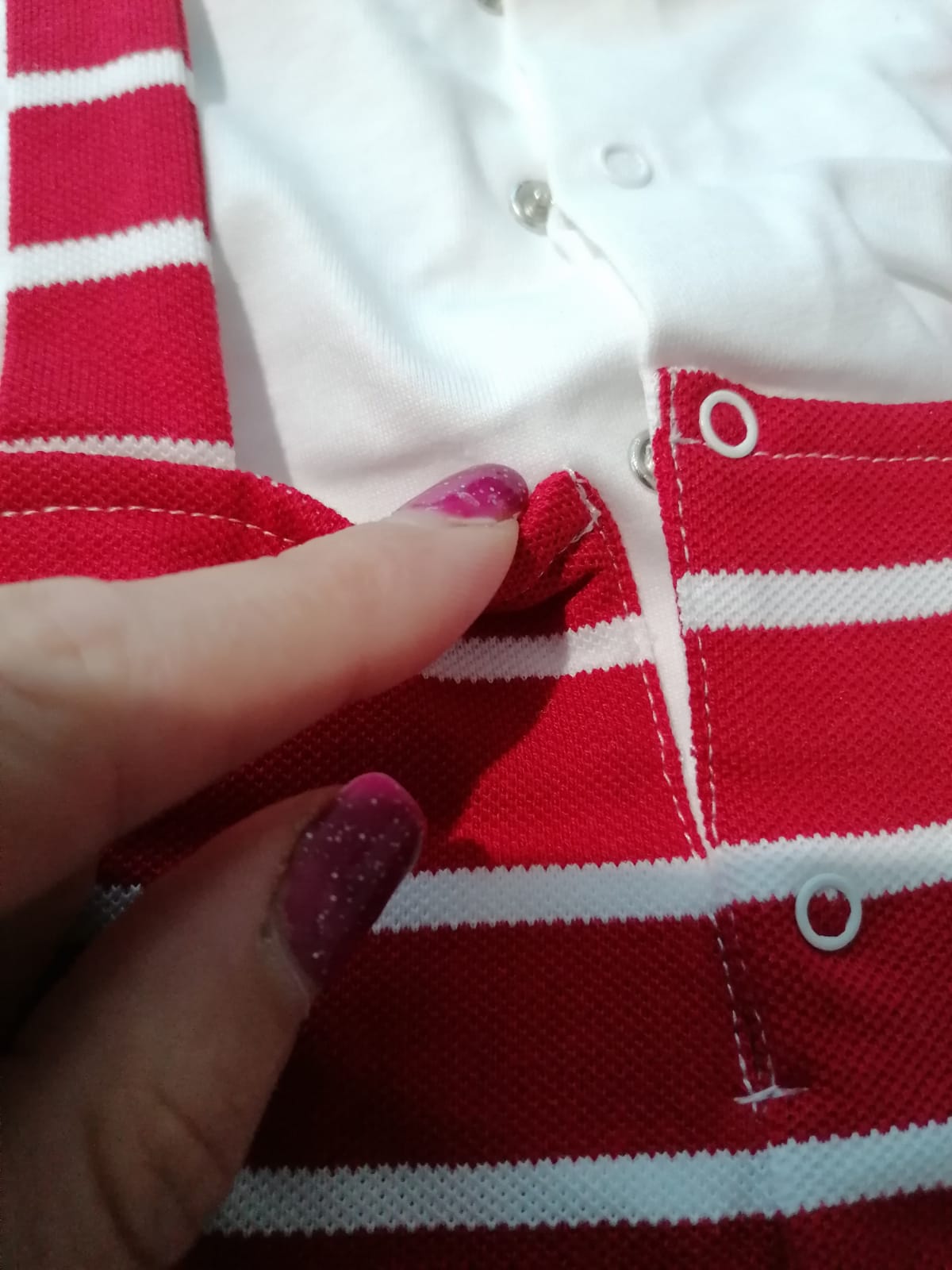 Peça de vestuário riscada vermelha e branca com mão segurando tecido