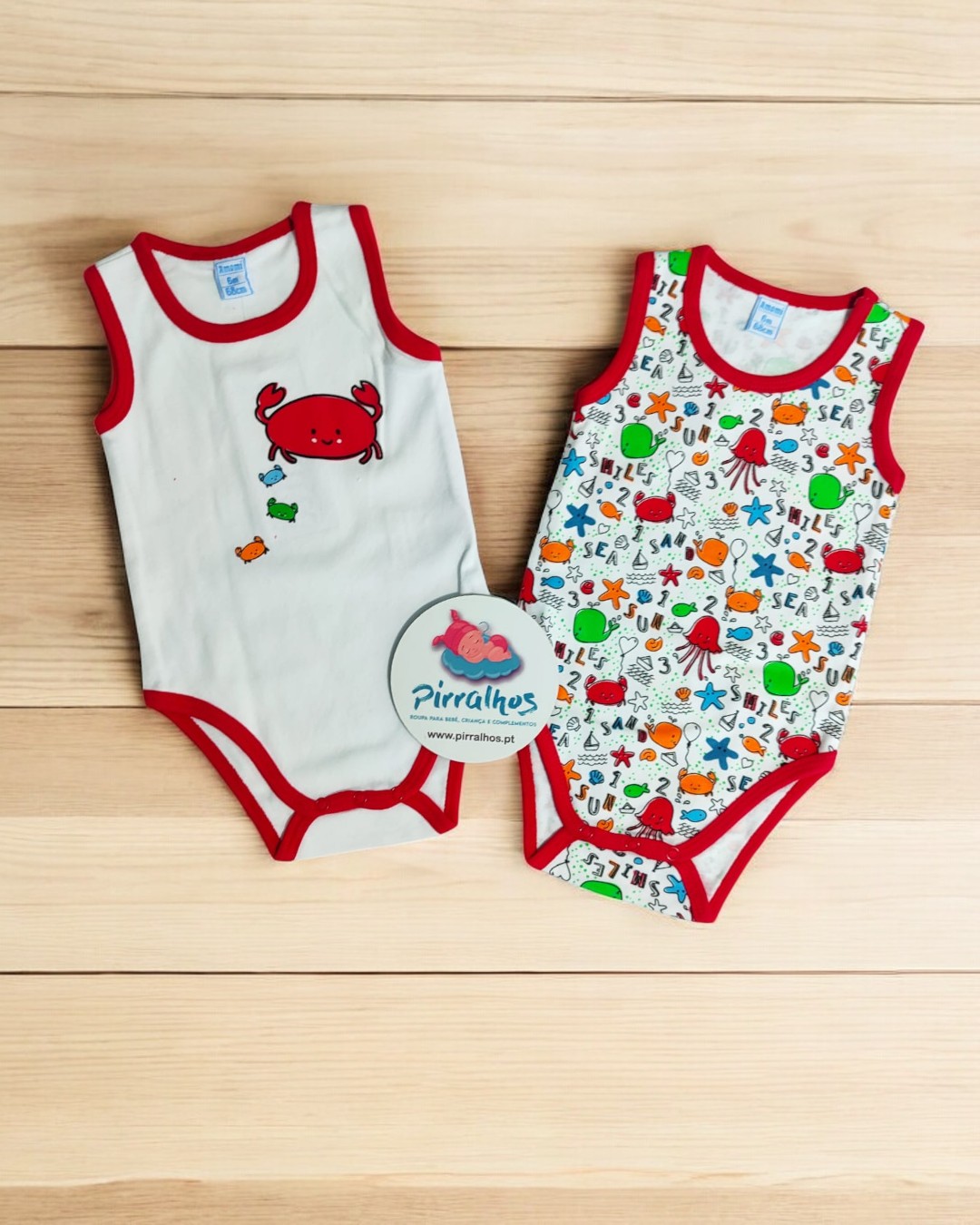 Dois bodies de criança com tema marinho sobre superfície de madeira clara