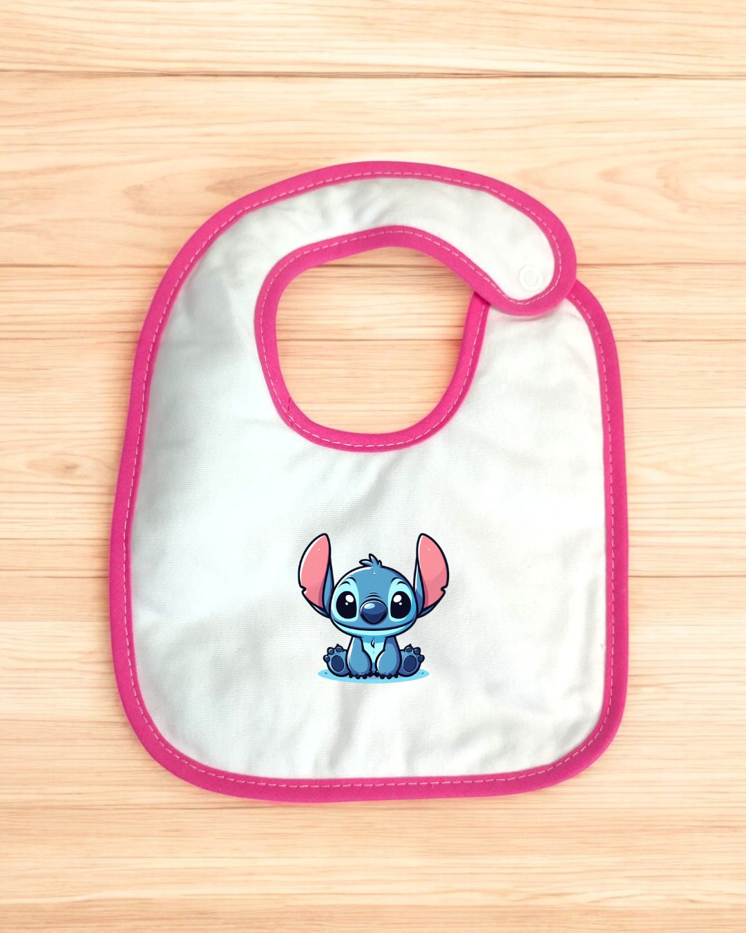 Babete branco com borda rosa e personagem Stitch azul desenhado no centro