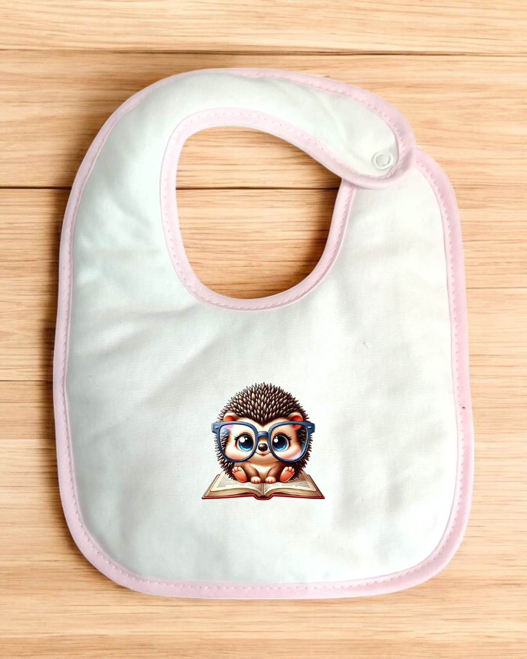 Babete branco com borda rosa e estampa de ouriço com óculos sentado sobre livro