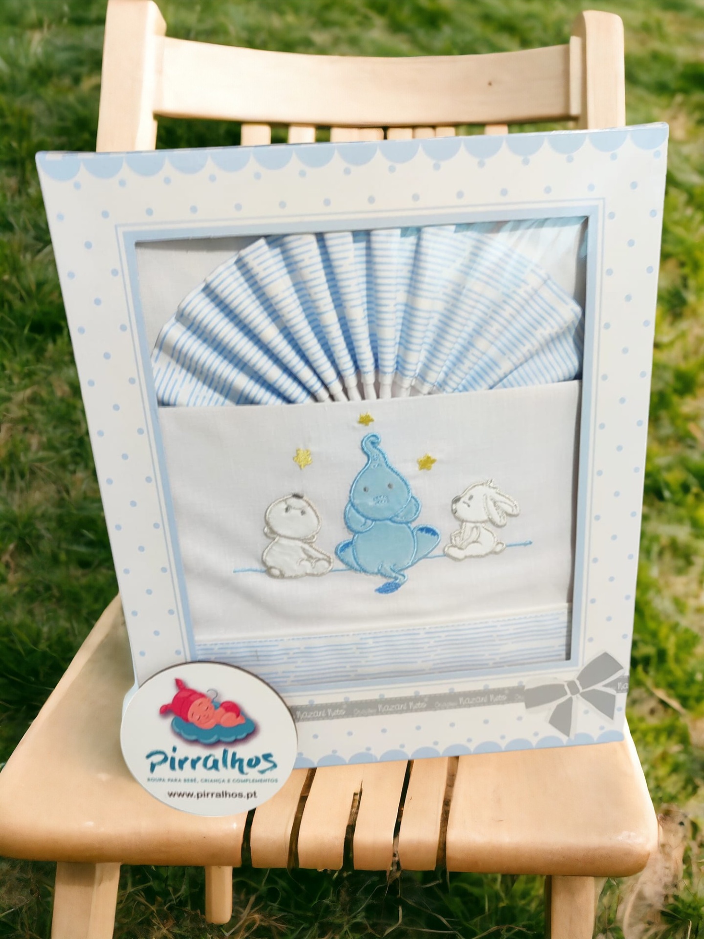 Conjunto de roupa de cama para bebé azul e branco com desenho bordado de elefante e coelhos numa embalagem decorativa.