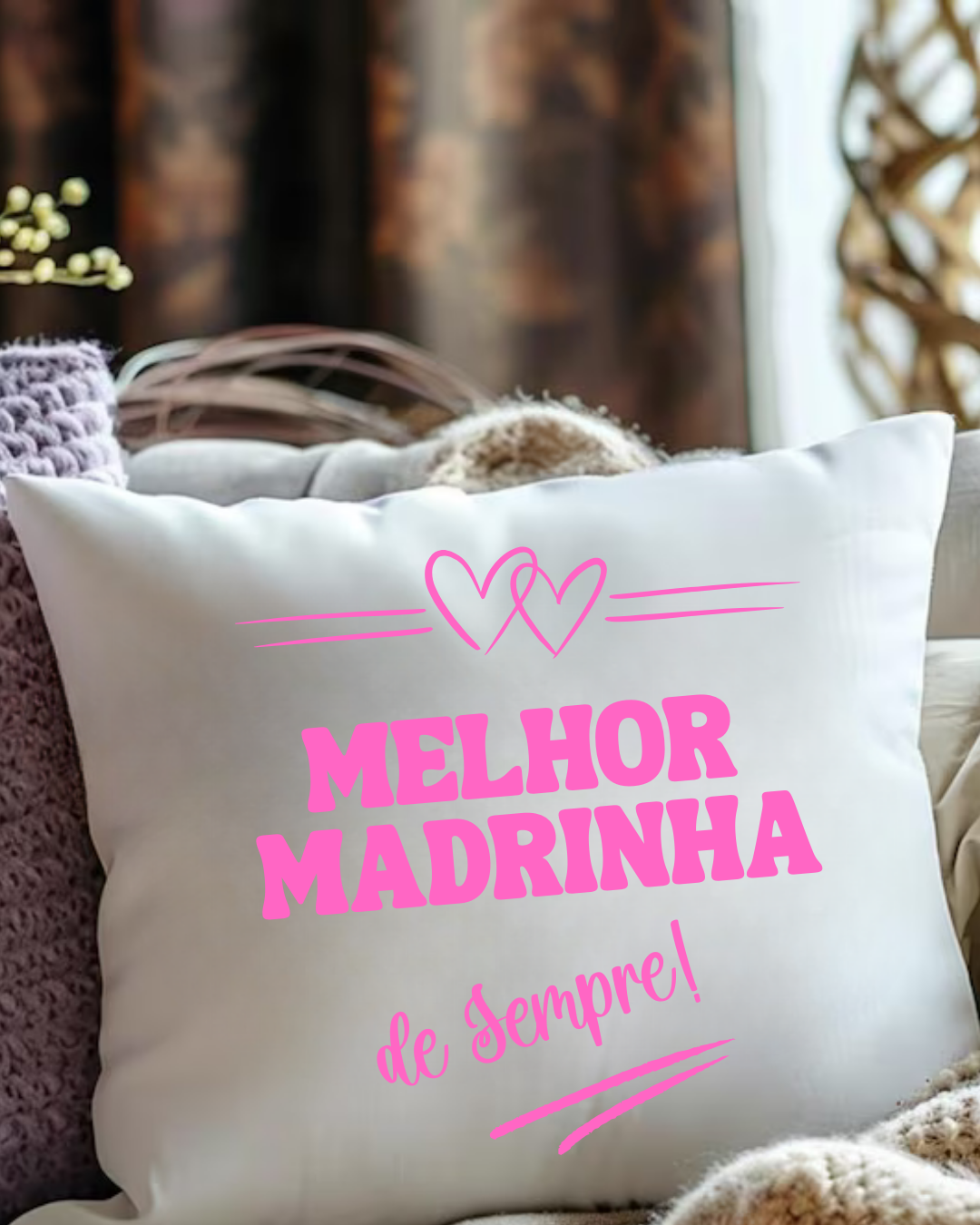 Almofada branca com texto rosa Melhor Madrinha de Sempre e dois corações em sofá com mantas