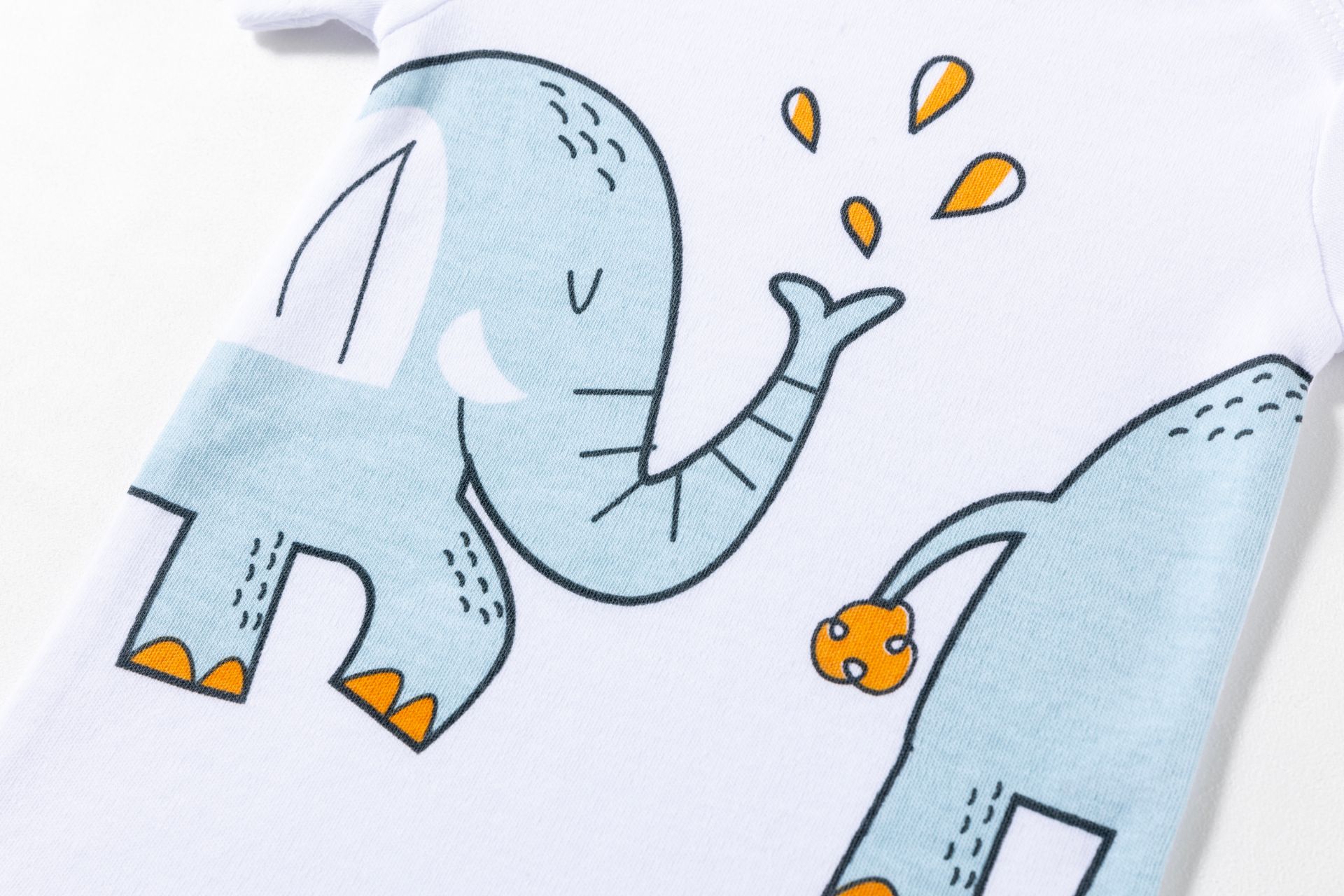 Detalhe de peça de roupa branca com estampa de elefantes azuis e detalhes em laranja