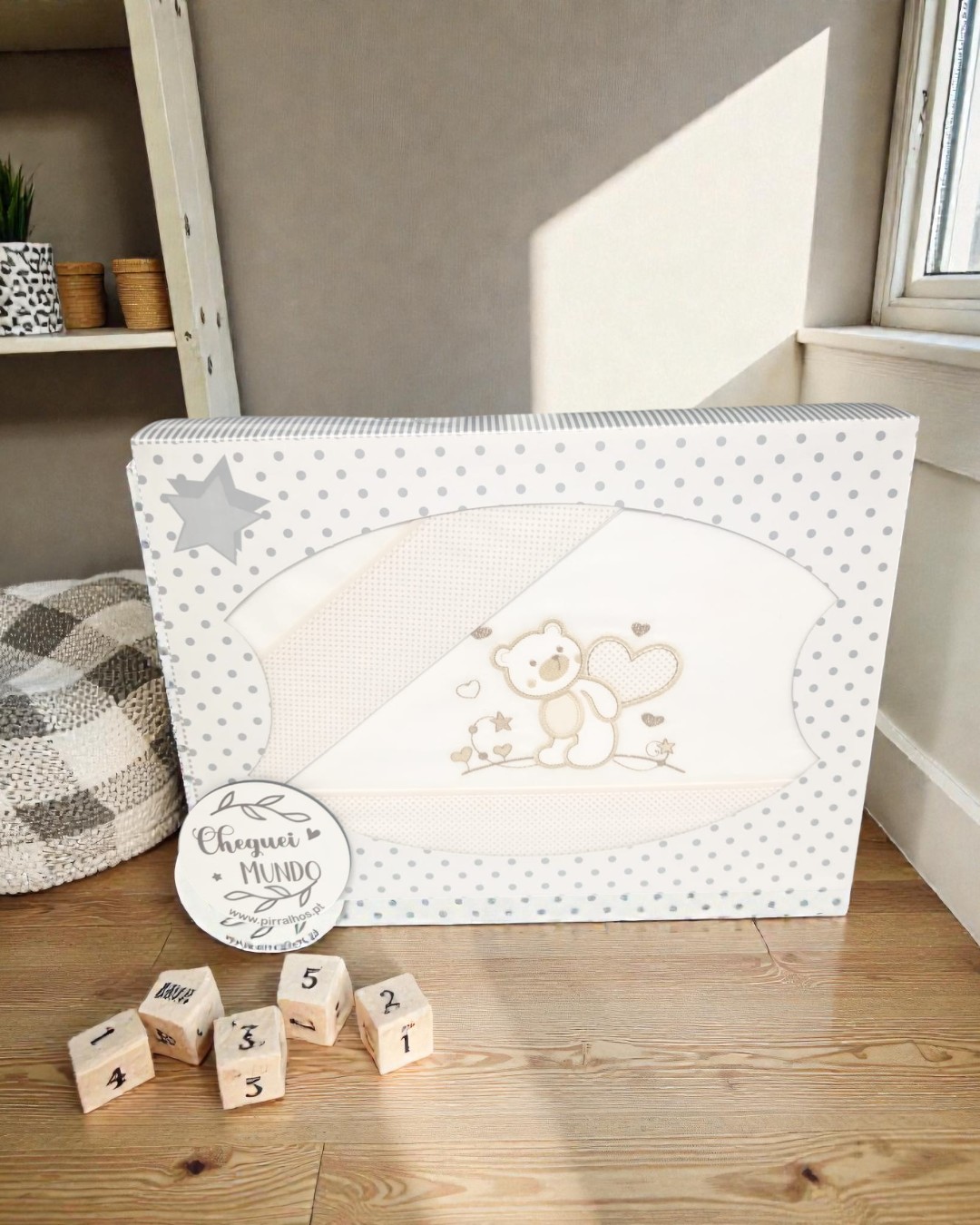 Caixa branca com pontos cinzentos e roupinha de bebé com ursinho estampado