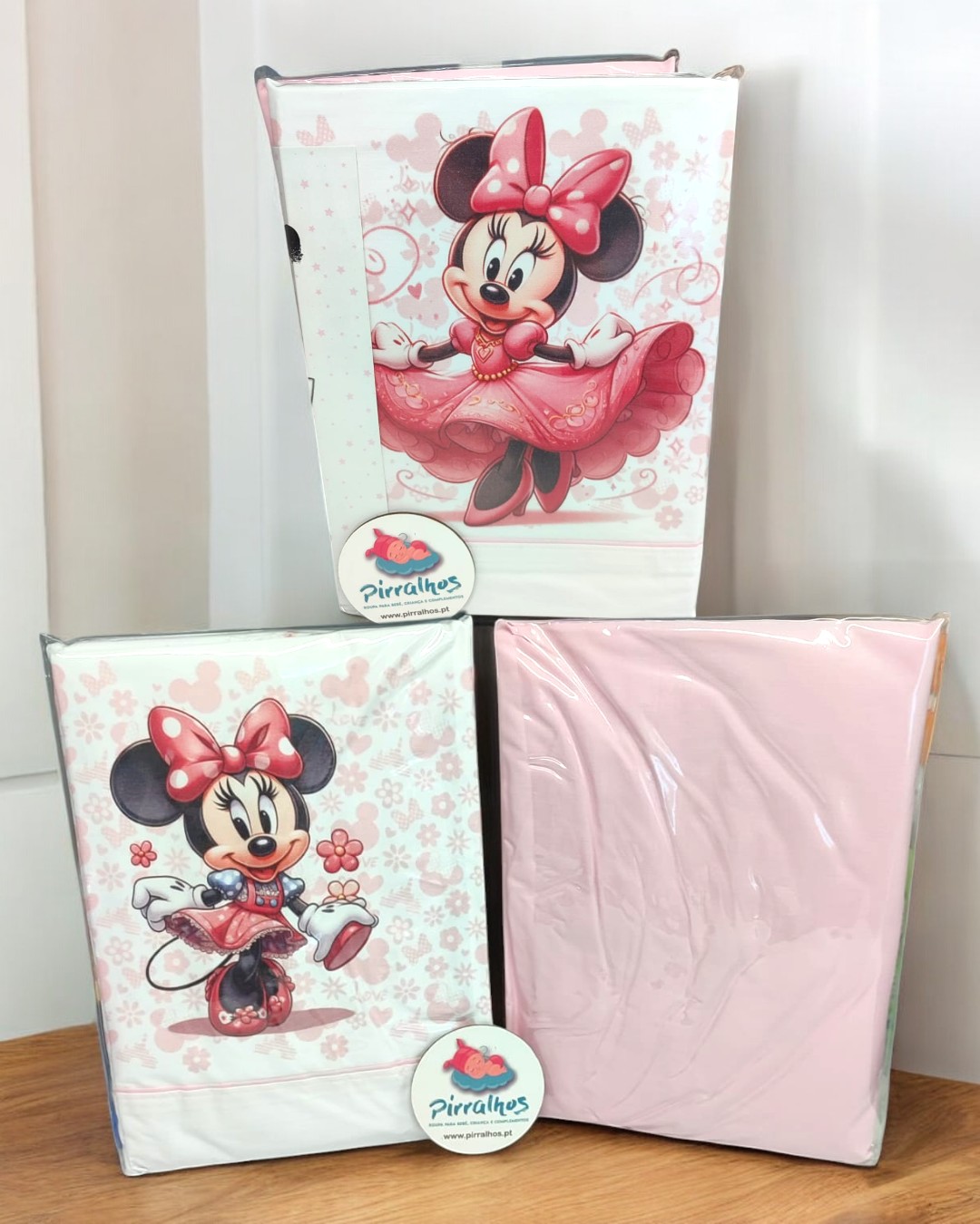 Conjuntos de roupa de cama rosa e branco com tema Minnie da Disney e embalagem com etiqueta 'Pirralhos'.