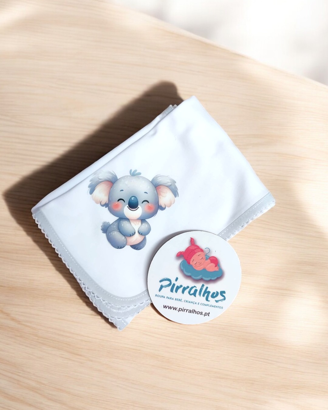 Manta branca com ilustração de coala e cartão redondo com logótipo Pirralhos