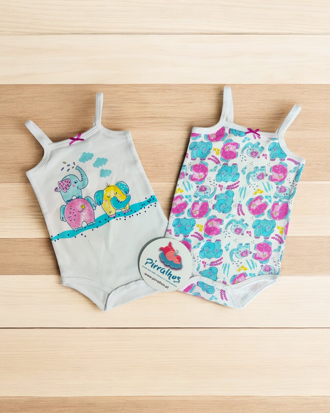 Dois bodies de bebé com temas de dinossauros em fundo de madeira clara