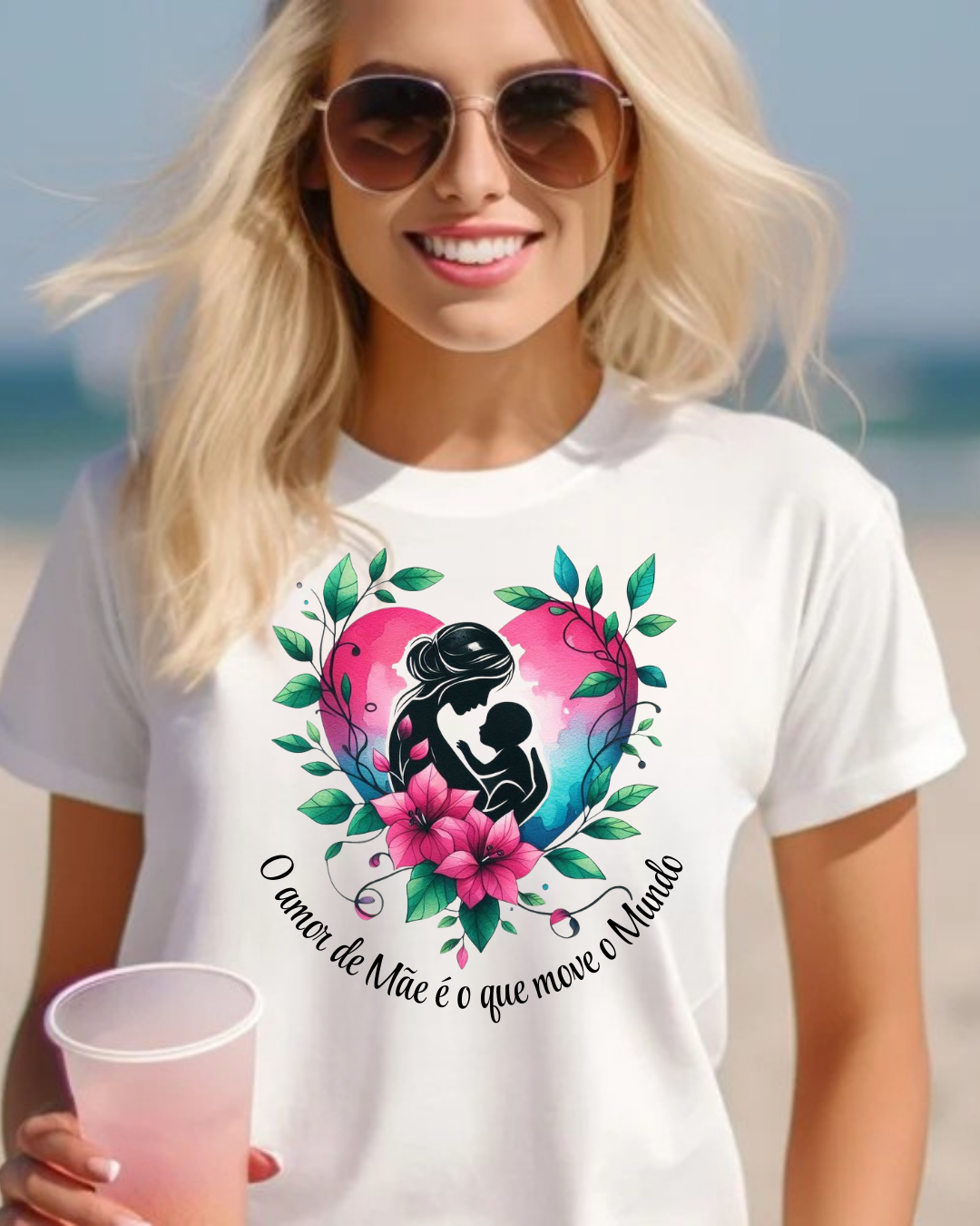 Mulher loira com óculos de sol usando t-shirt branca com estampa colorida de mãe e filho dentro de coração e texto em português.