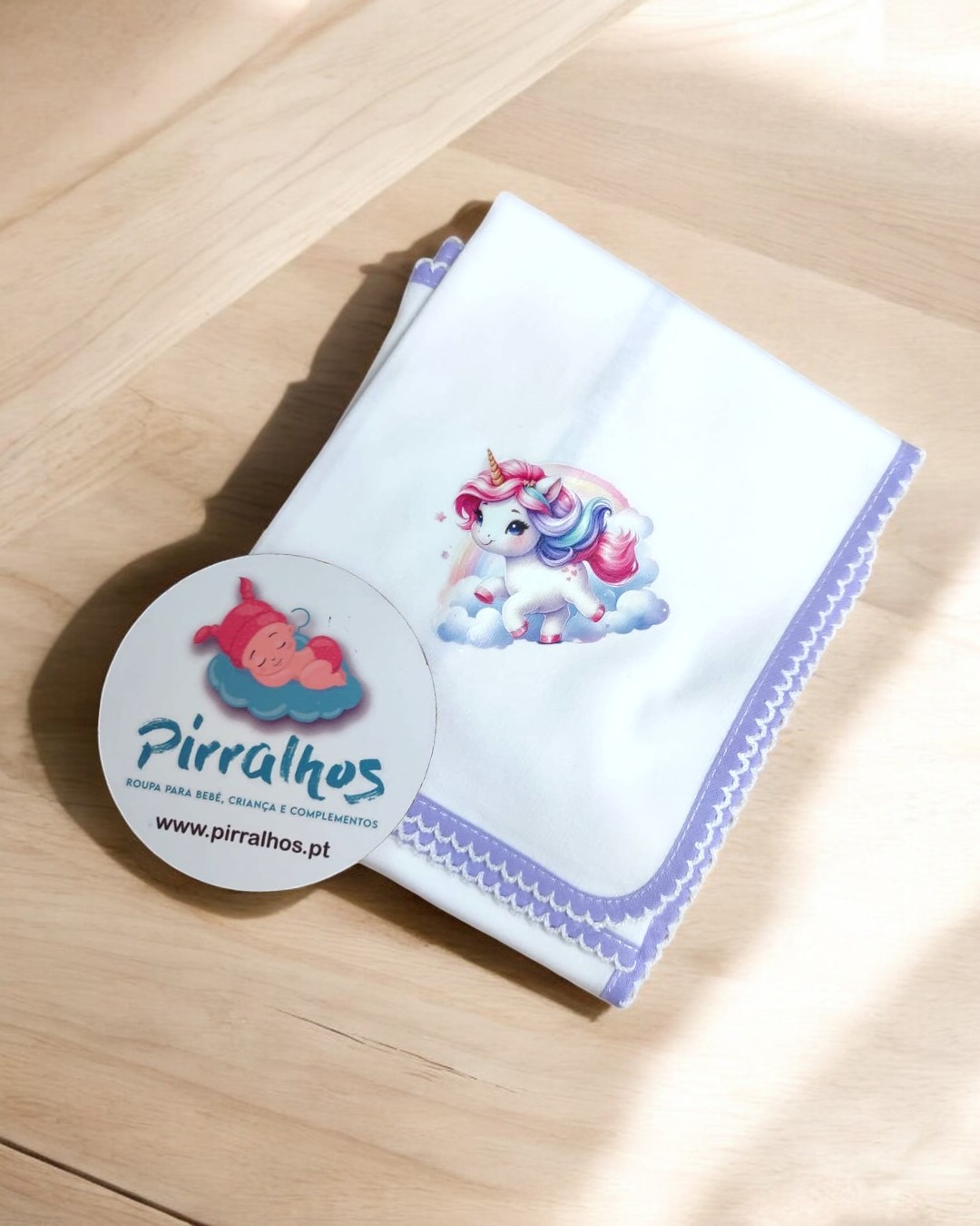 Fralda branca com unicórnio colorido e borda lilás, cartão da marca Pirralhos