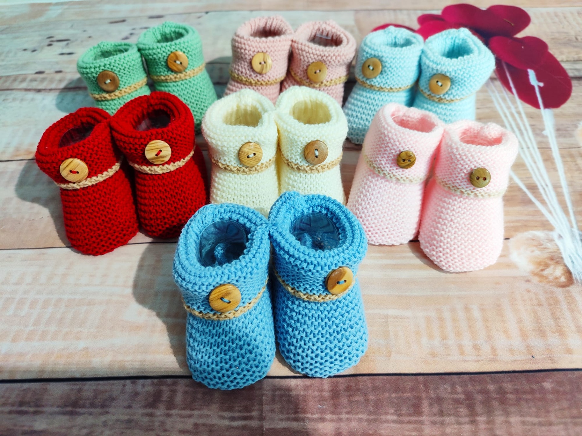 Dez pares de sapatinhos de bebé em várias cores feitos à mão em tricô com botões de madeira