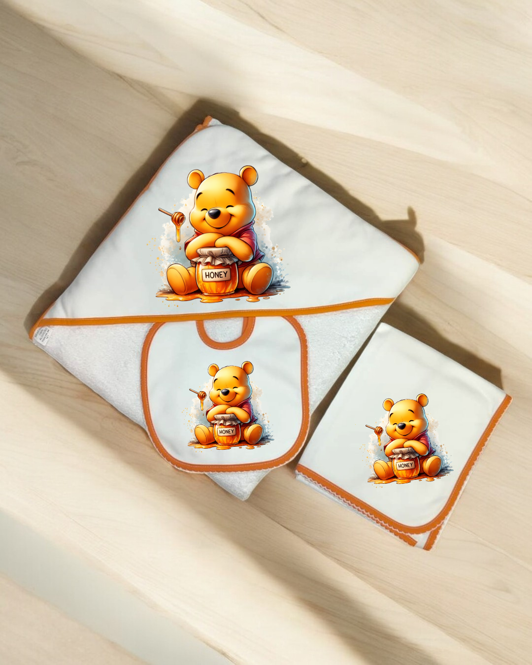 Conjunto de toalha, babete e fralda com imagem do ursinho Winnie the Pooh e pote de mel