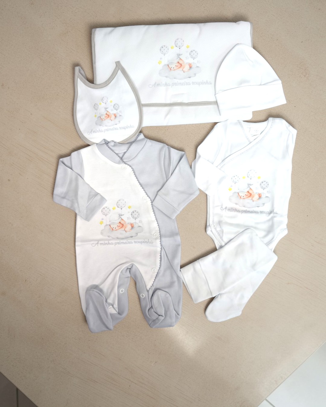 Conjunto de roupa de bebé com estampado de bebé dormindo em nuvem e texto A minha primeira roupinha.