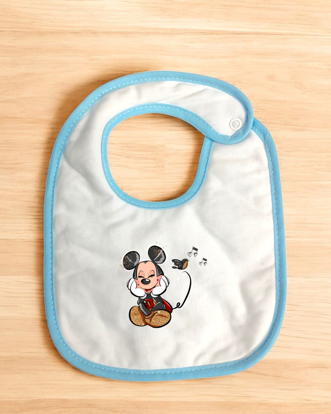 Babete branco com borda azul e desenho do Mickey Mouse a ouvir música