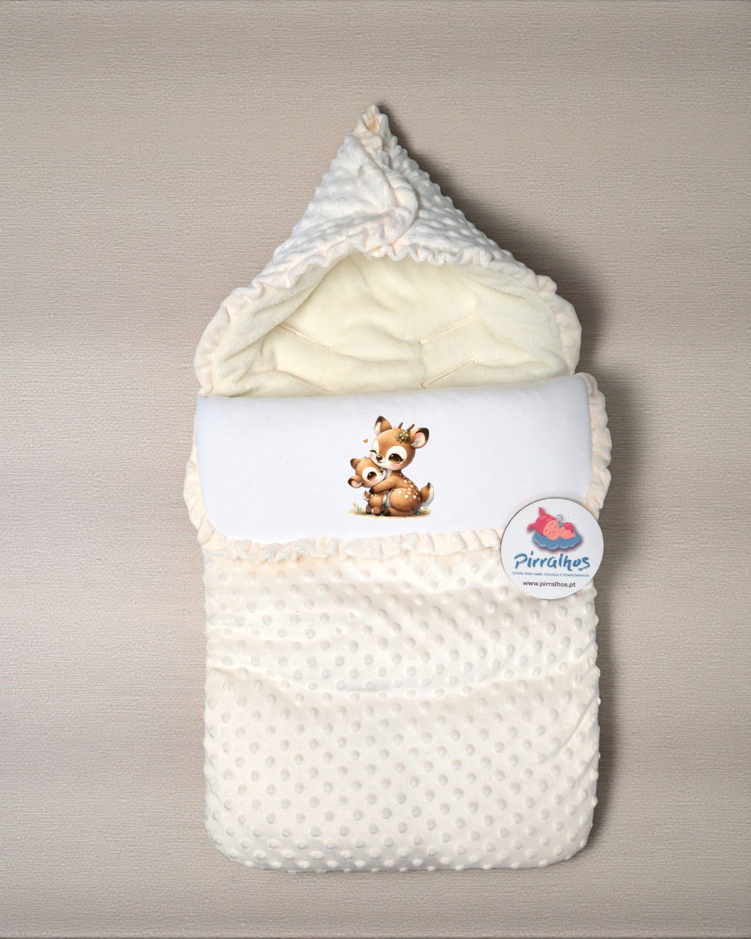 Saco de bebé branco com textura pontilhada e capuz, decorado com desenho de veados e etiqueta Pirralhos