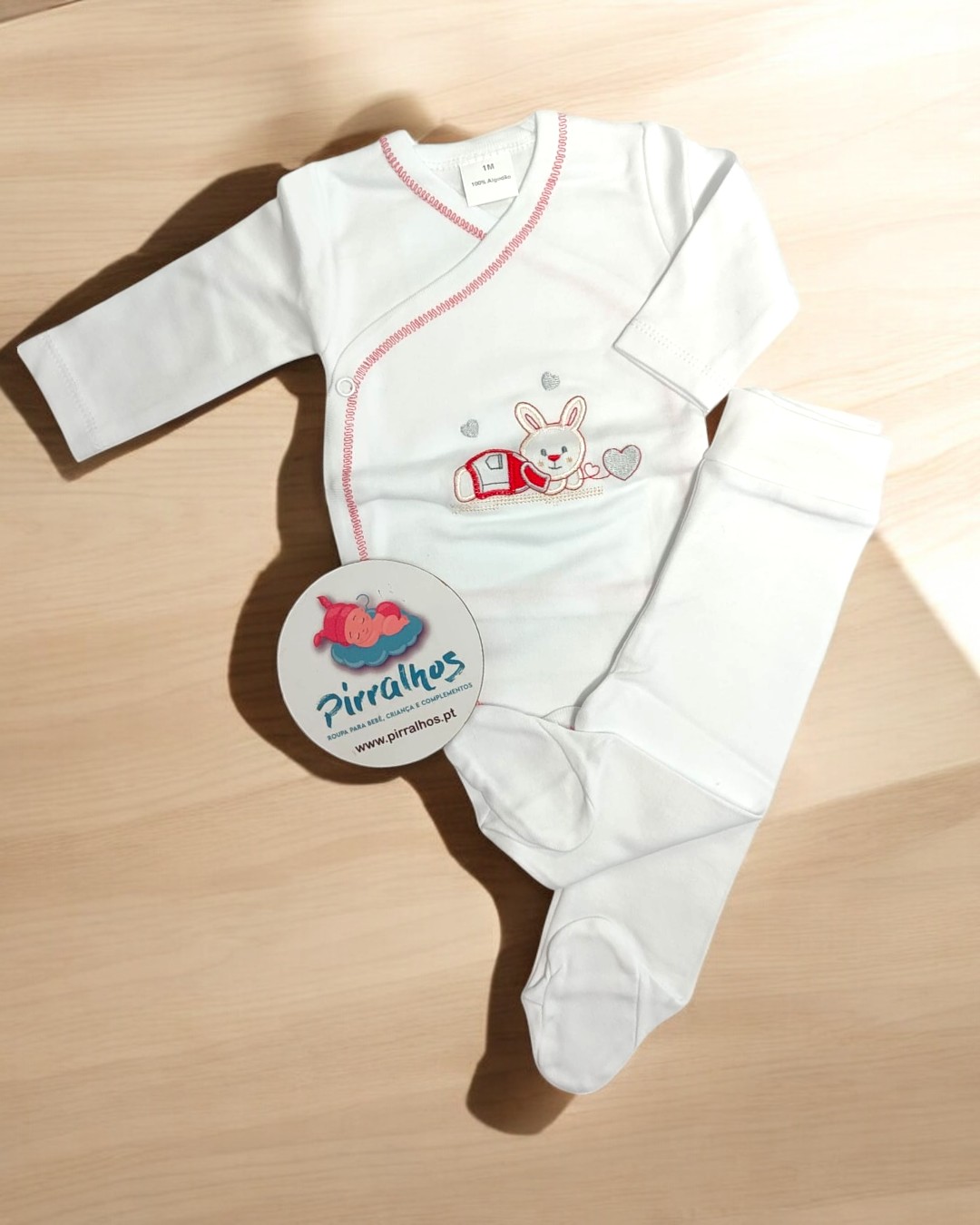 Conjunto de roupa de bebé branco com bordado de coelho e calças com pés em madeira clara