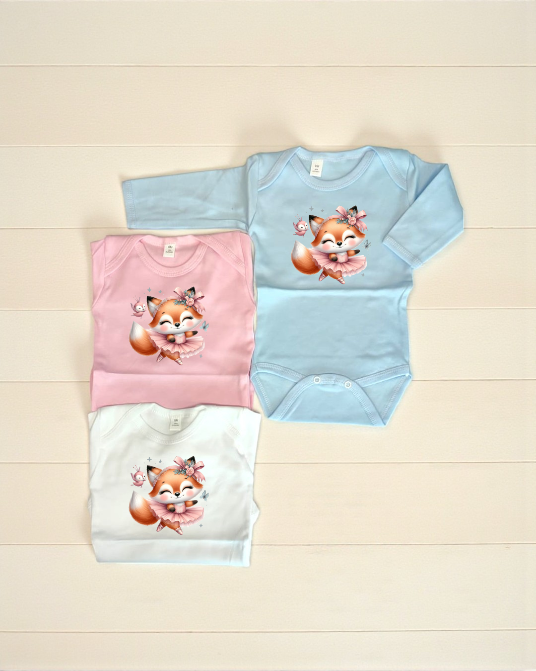 Bodies de bebé azul, rosa e branco com desenho de raposa bailarina e passarinho.