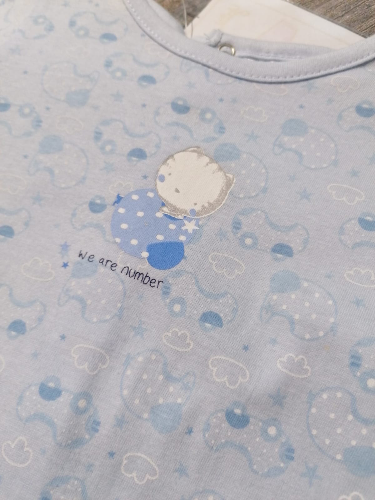 Camisola azul clara com padrão de nuvens, ursinho e texto 'We are number'