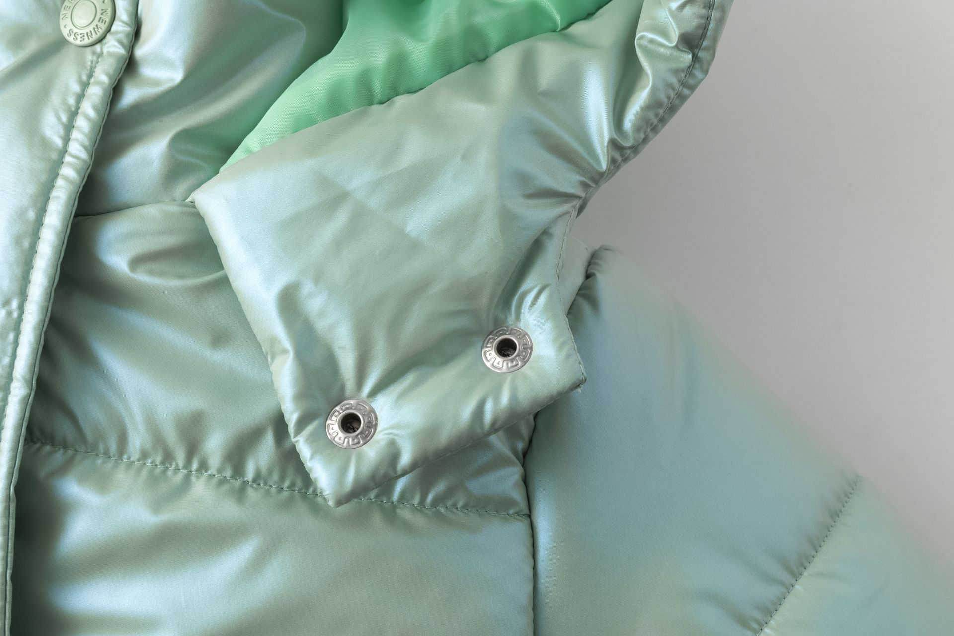 Casaco verde-água brilhante com botões metálicos e costuras acolchoadas