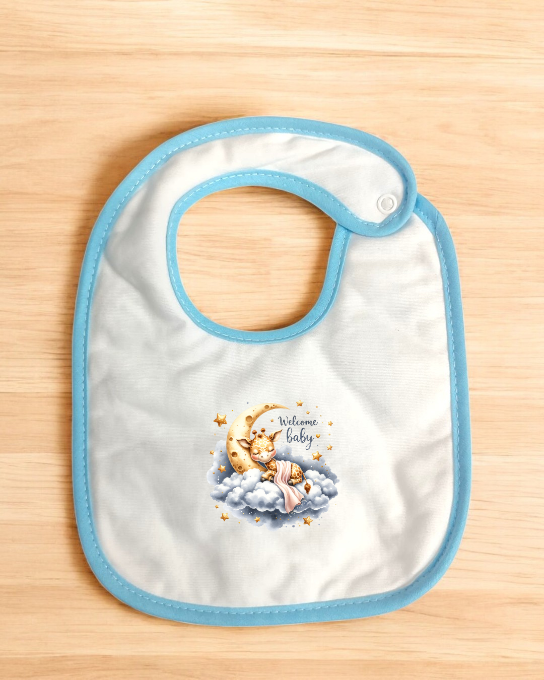 Babete de tecido branco com borda azul e estampa de lua, nuvem e texto 'Welcome Baby'