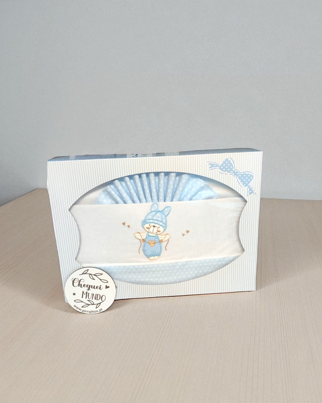 Conjunto de bebé azul e branco com bordado de ursos em caixa branca com riscas azuis