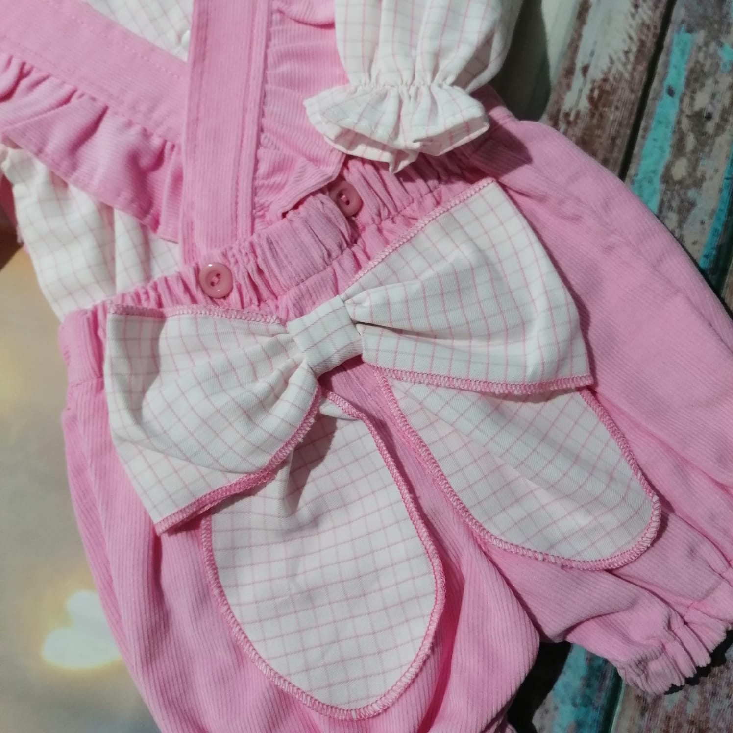 Roupa de bebé cor-de-rosa com laço e padrão de riscas