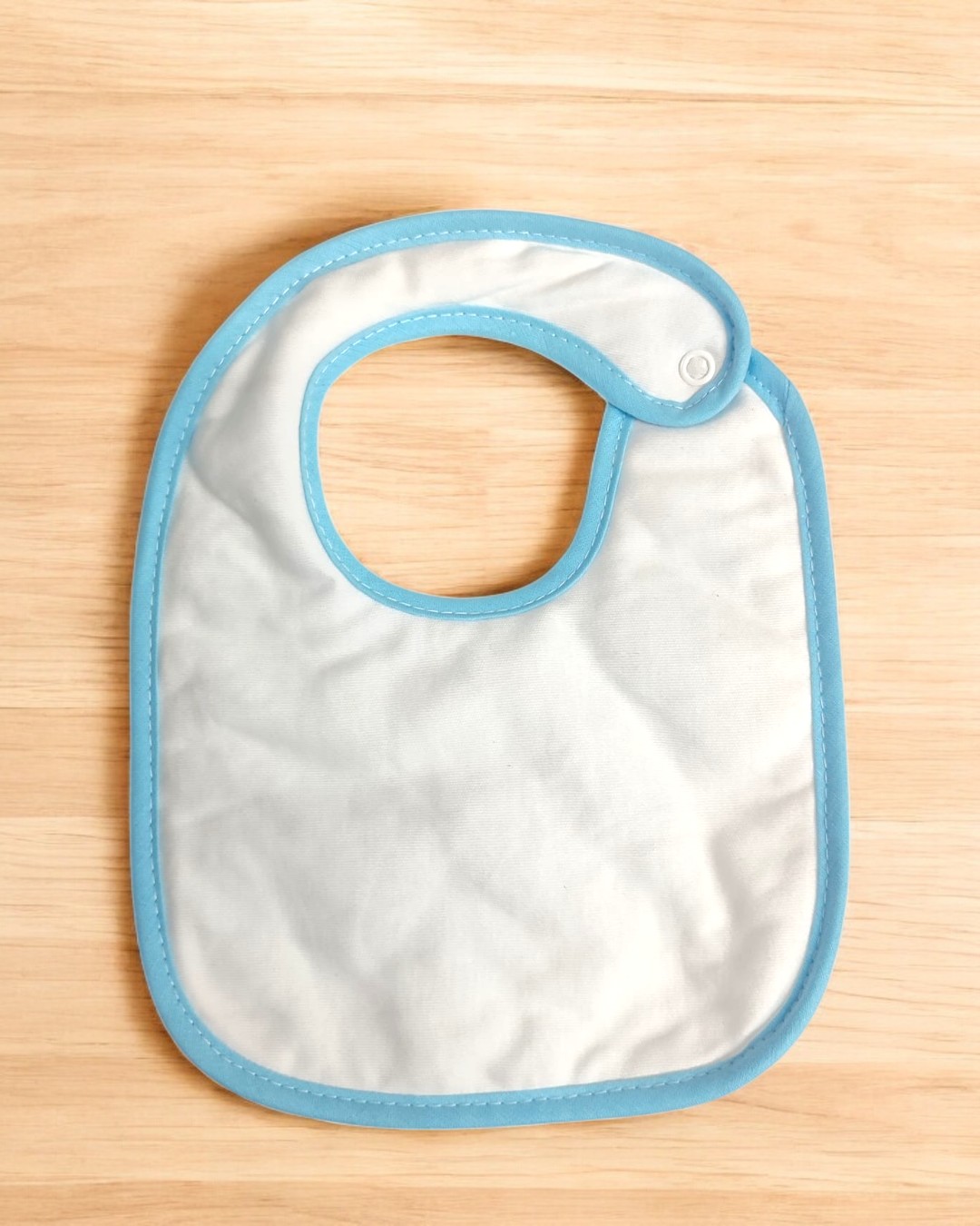 Babete branco com borda azul sobre superfície de madeira