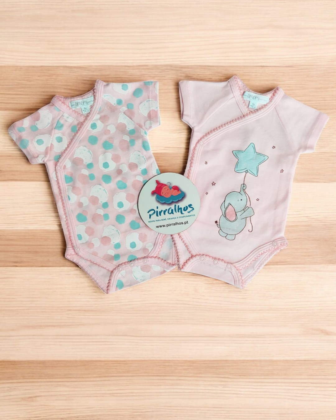 Dois bodies para bebé em algodão, um com padrão de bolinhas coloridas e outro rosa com elefante azul