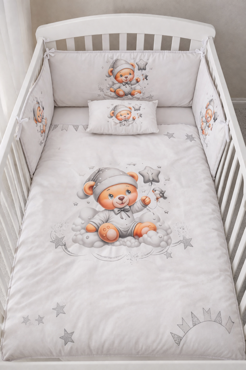 Conjunto de cama para berço branco com estampa de ursinho em pijama cinza segurando balão em forma de estrela