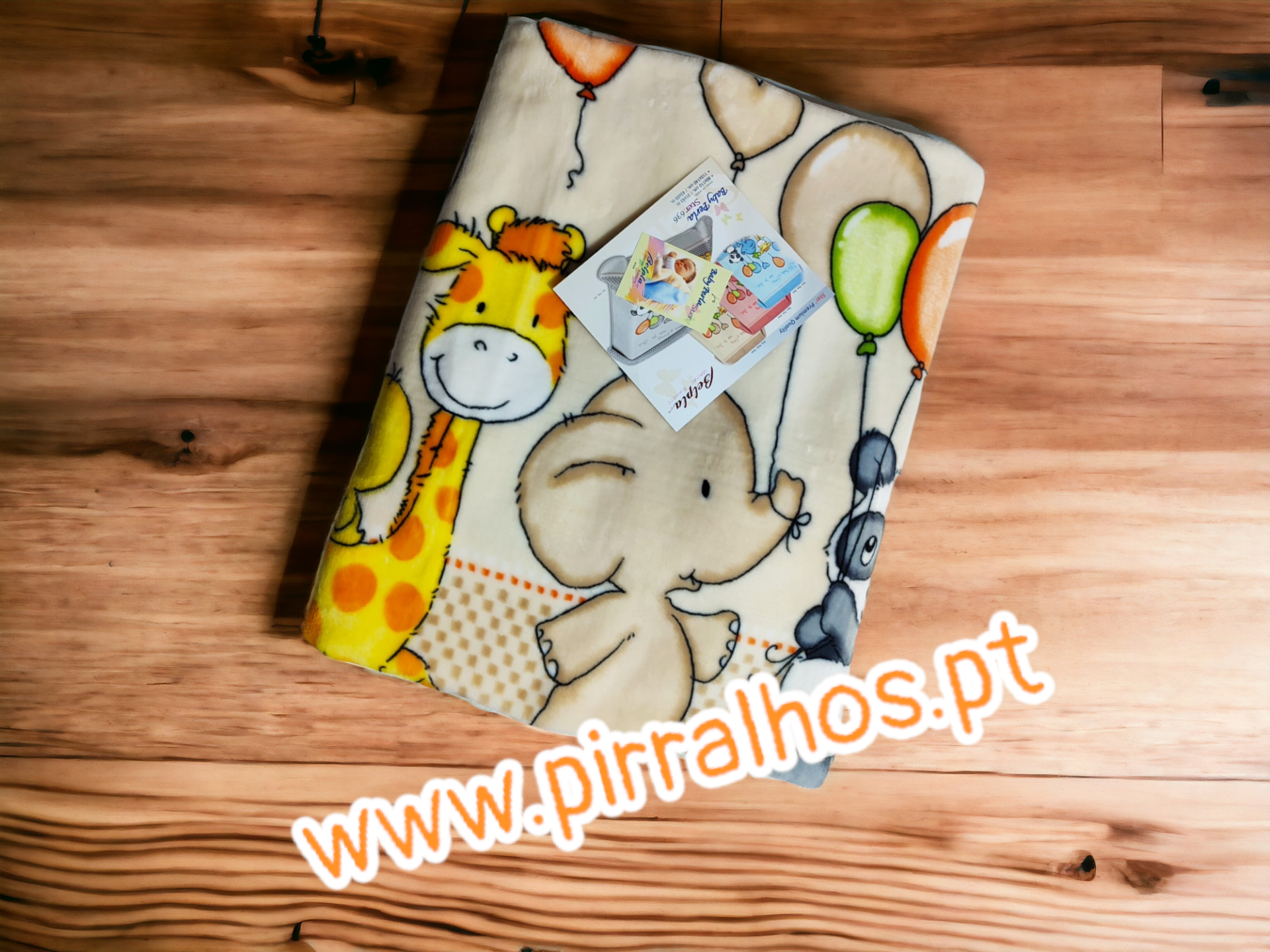 Manta infantil com desenhos de animais e balões sobre piso de madeira