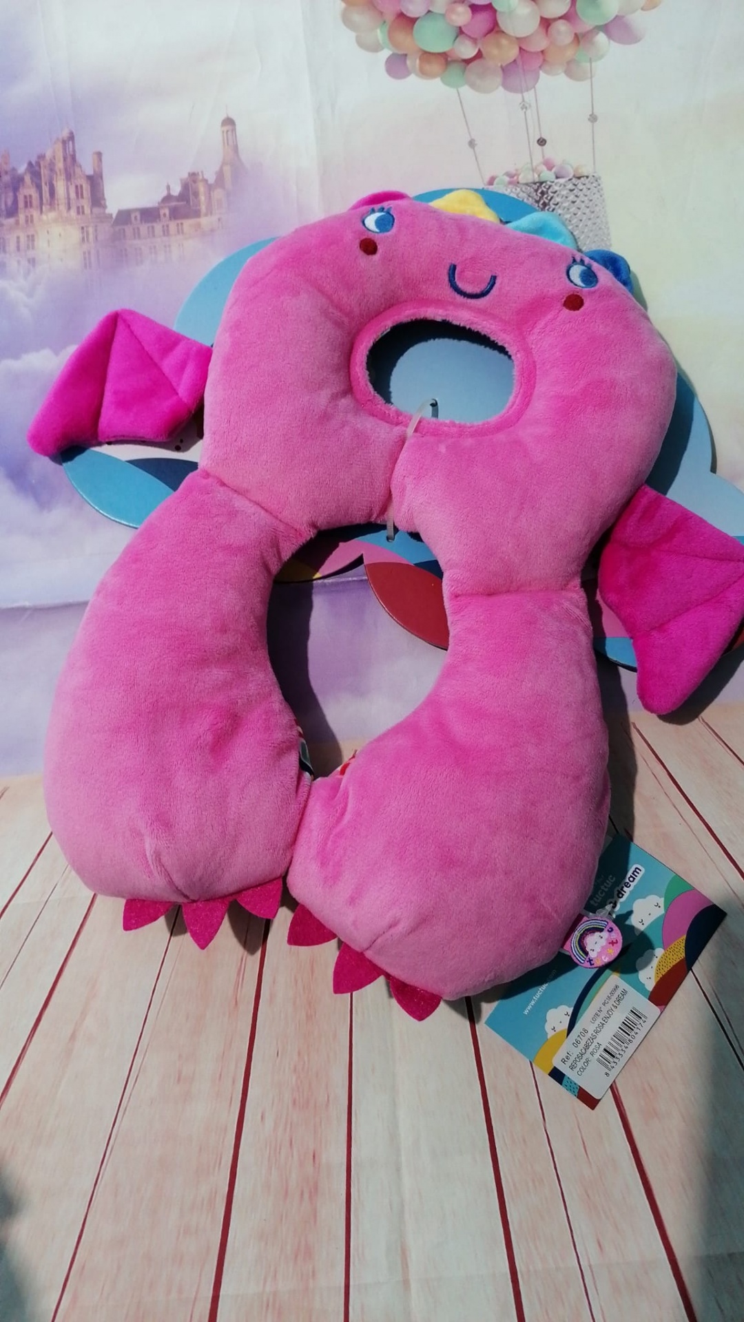 Travesseiro de pescoço rosa em pelúcia com rosto sorridente e asas