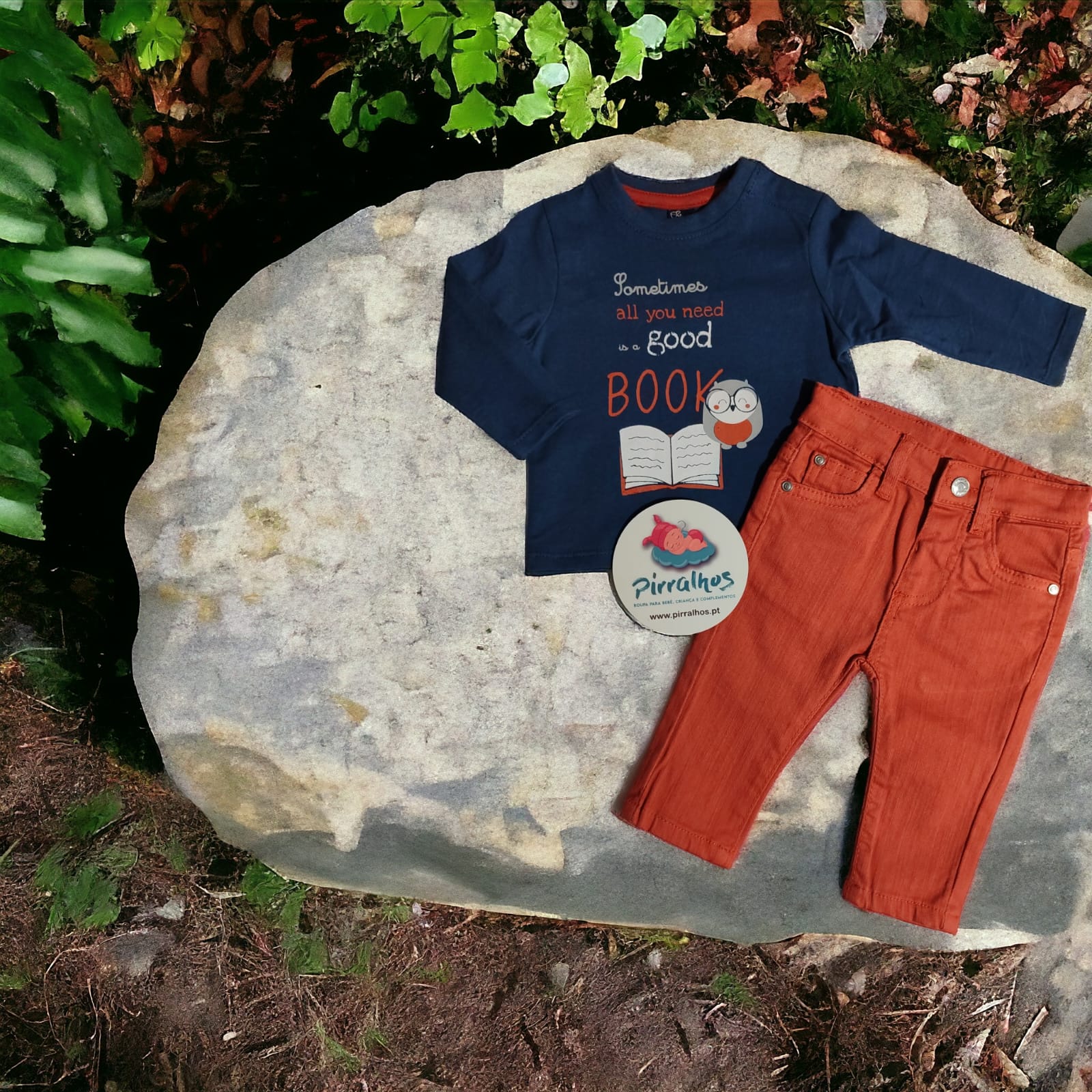 Conjunto de roupa infantil azul e laranja sobre pedra ao ar livre