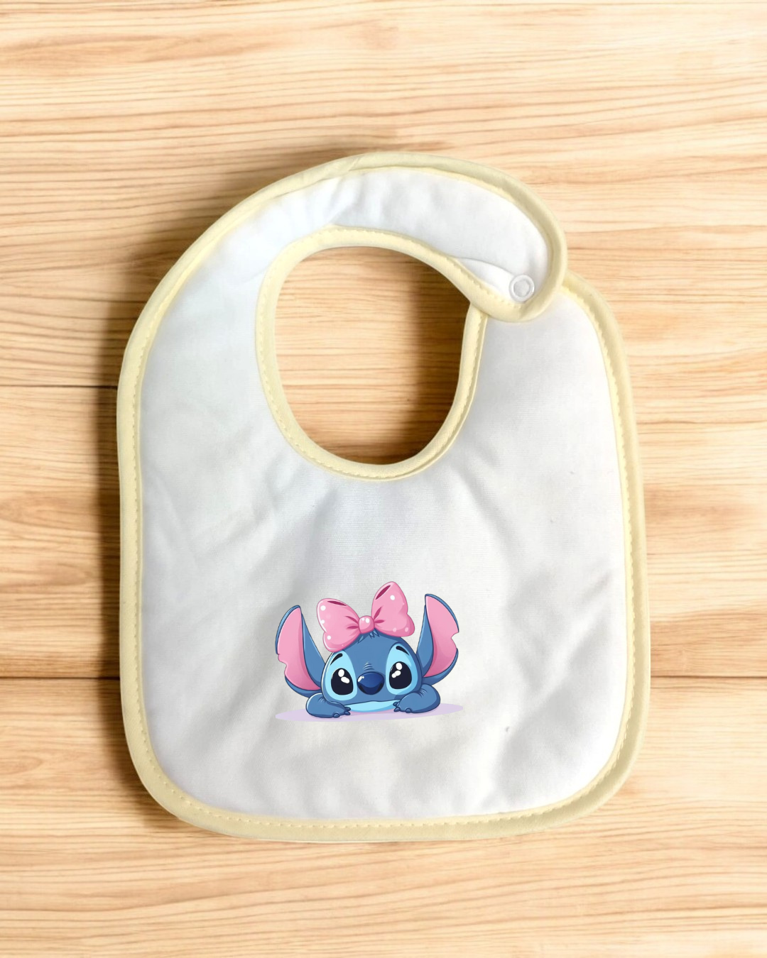 Babete branco com borda amarela e personagem Stitch com laço cor-de-rosa