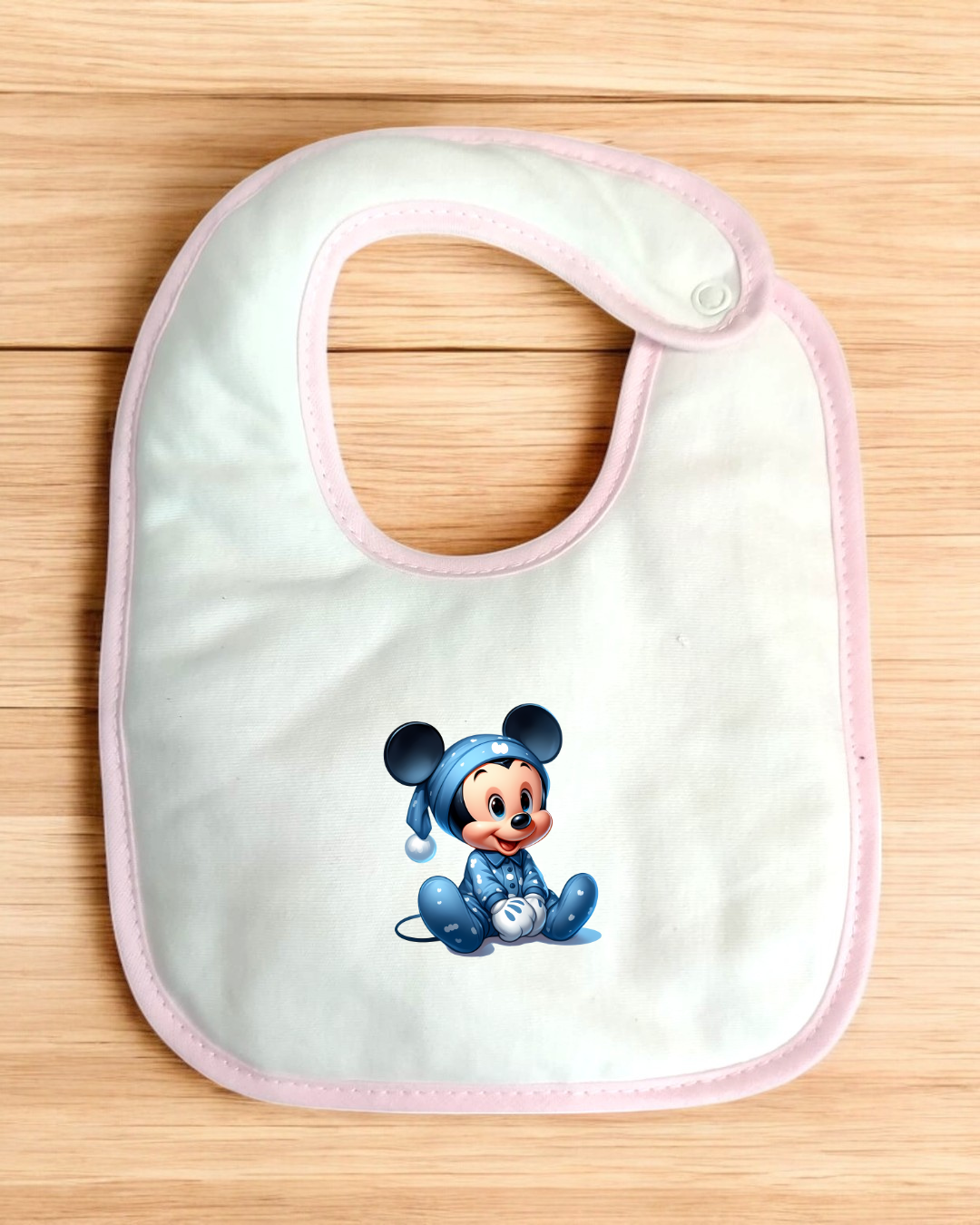 Babete branco com borda rosa e estampa de rato bebé vestido com pijama azul