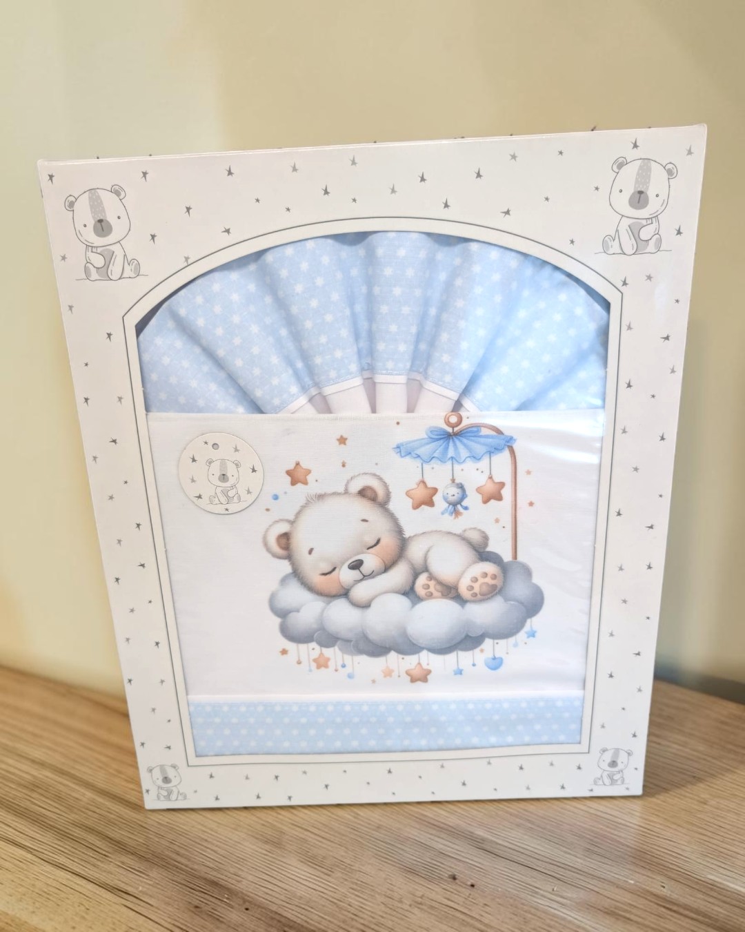 Conjunto de roupa de bebé azul com estrelas e ursinho a dormir em caixa decorada.