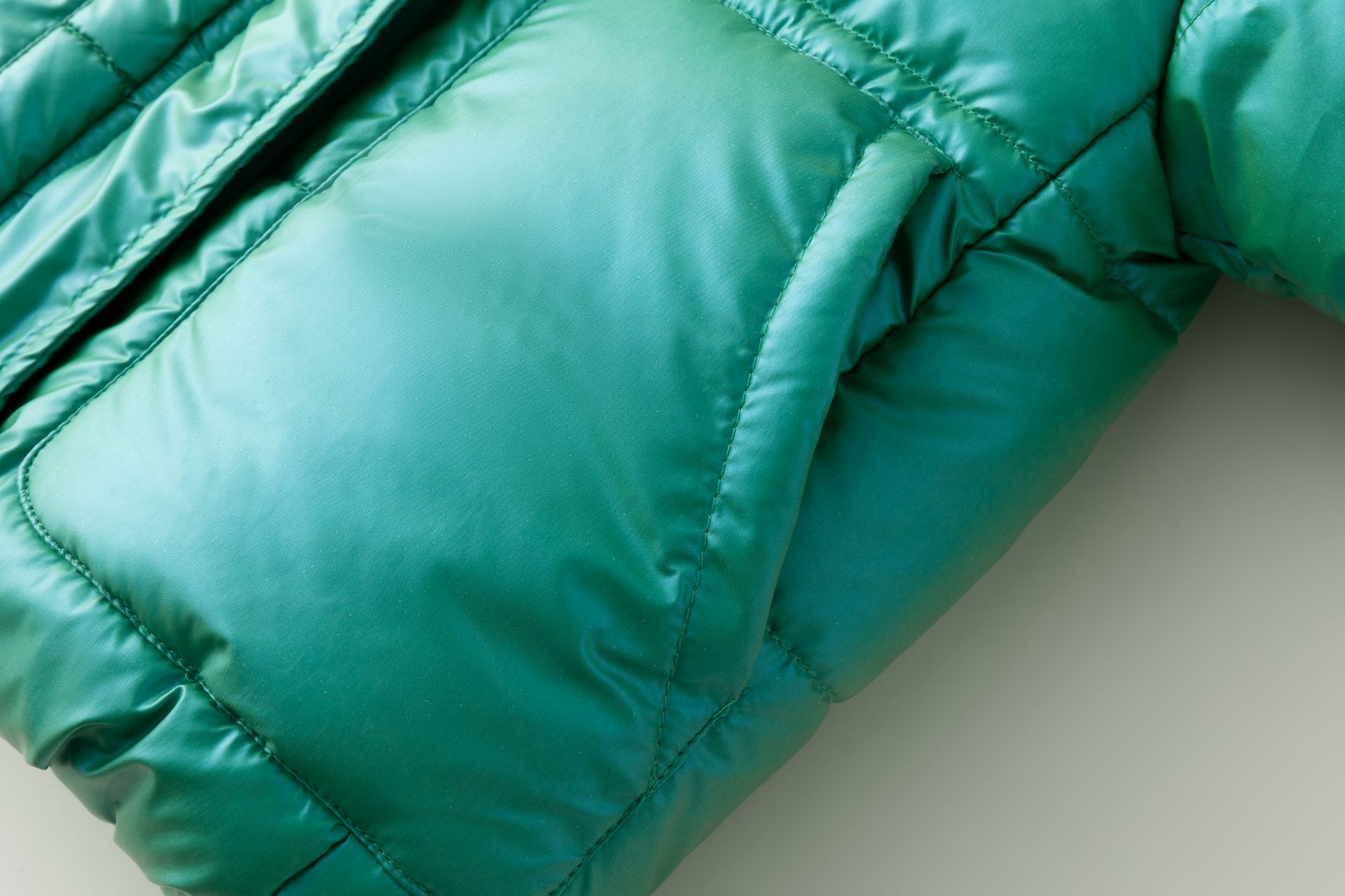 Manga de casaco acolchoado verde esmeralda sobre fundo claro