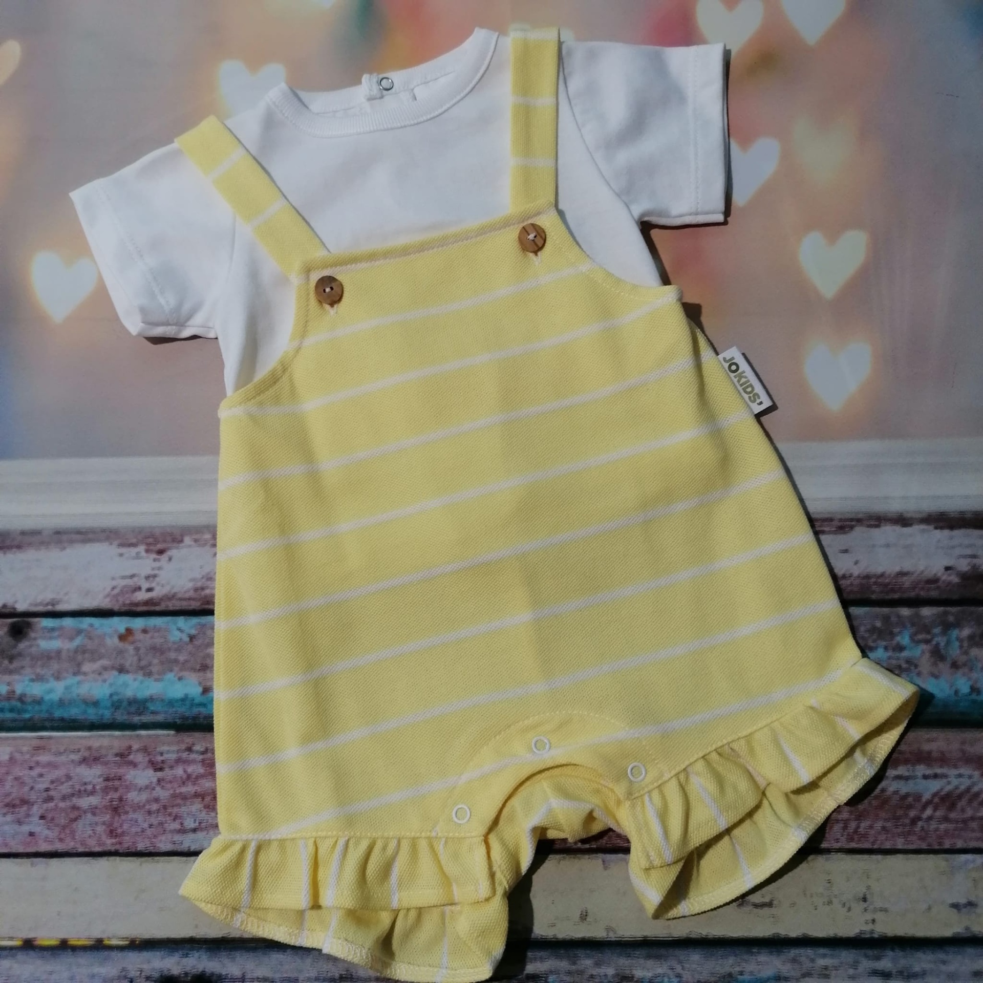Conjunto de roupa para bebé branco com macacão amarelo claro com riscas e folhos
