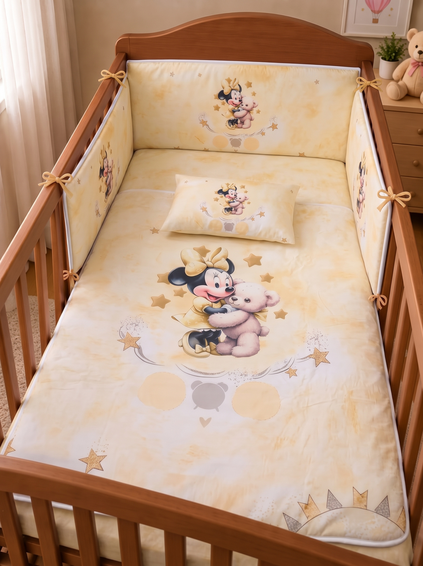 Roupa de berço amarela com estampa da Minnie Mouse a abraçar um ursinho e estrelas douradas em berço de madeira clara