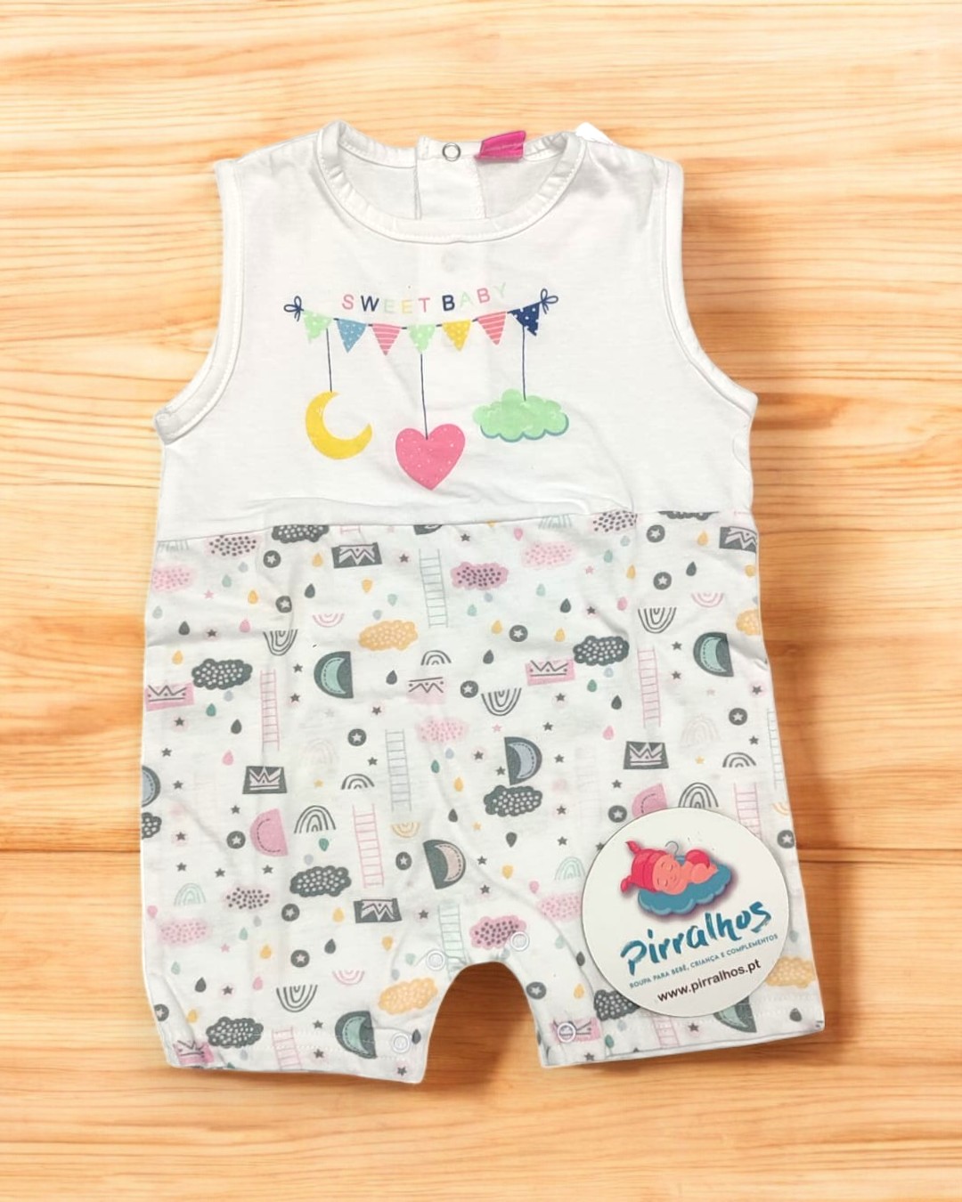 Macacão de bebé branco com padrão colorido na parte inferior e etiqueta 'Pirralhos'