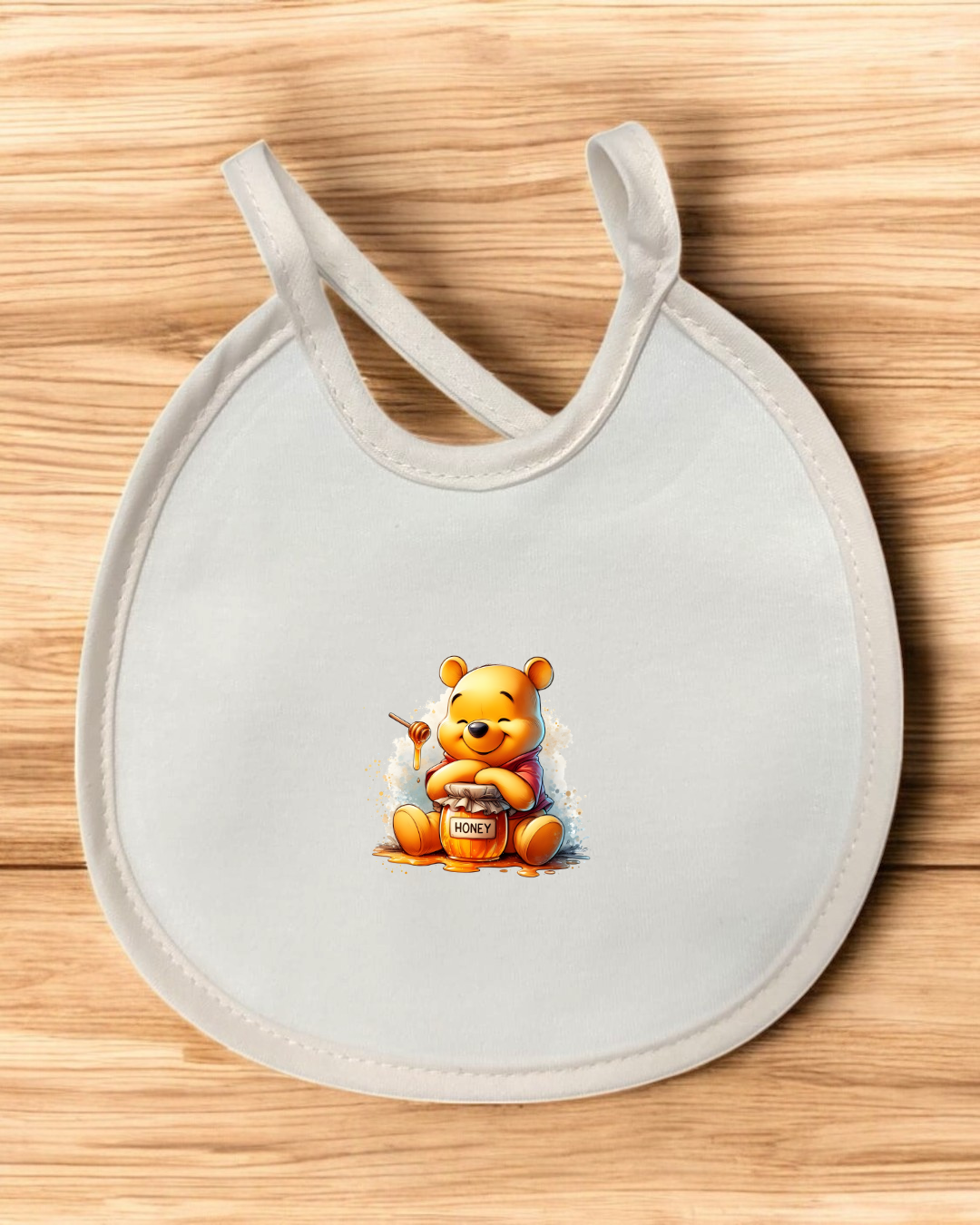 Babete branco com imagem do ursinho Pooh segurando pote de mel