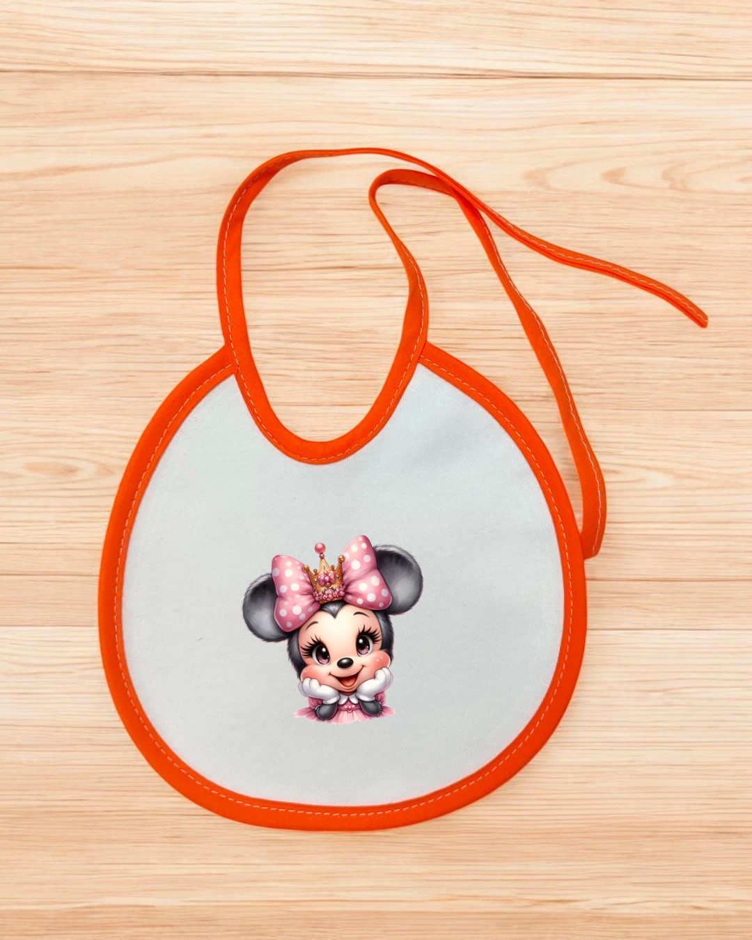 Babete branco com bordas e atilhos laranja com personagem infantil estampada