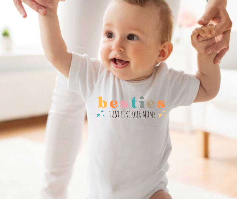 Bebé com camisola branca estampada com texto colorido a ser ajudado a andar