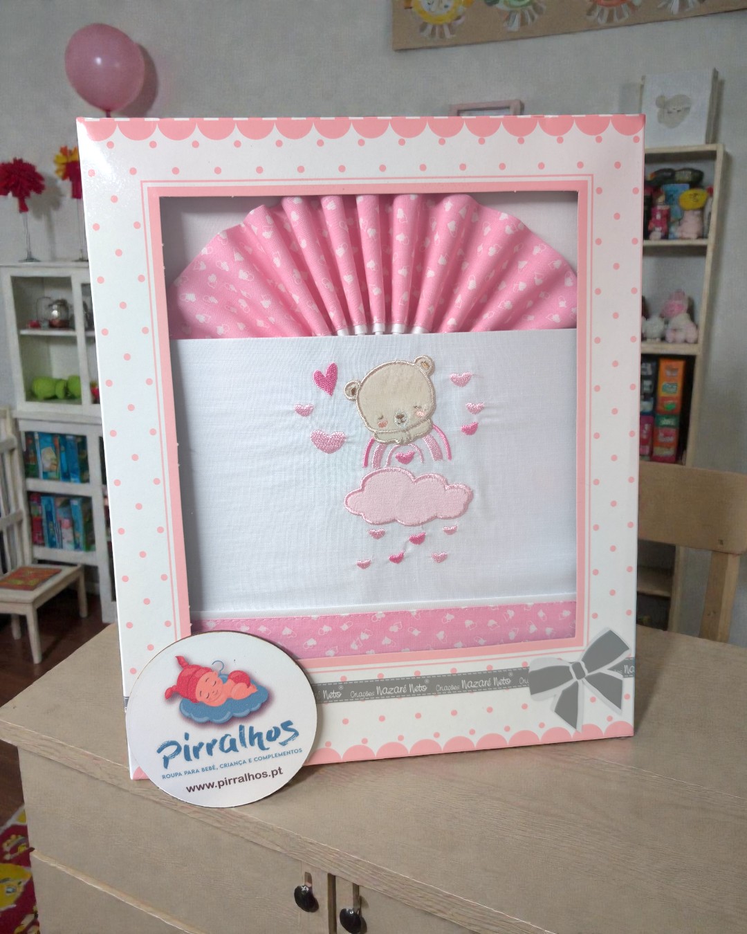 Fralda de bebé branca e rosa com bordado de urso em caixa rosa com bolinhas