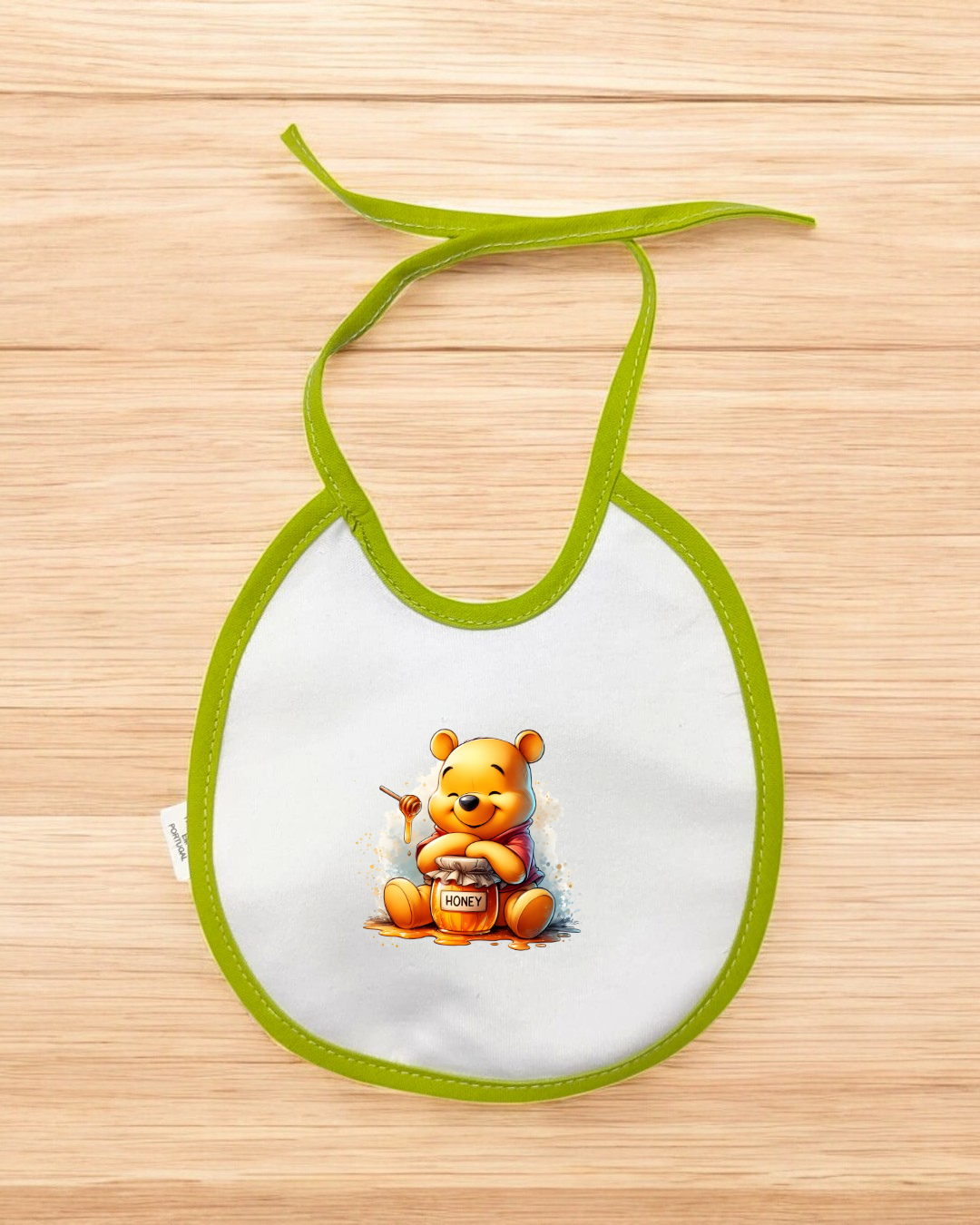 Babete branco com bordas verdes e imagem do Winnie the Pooh com pote de mel