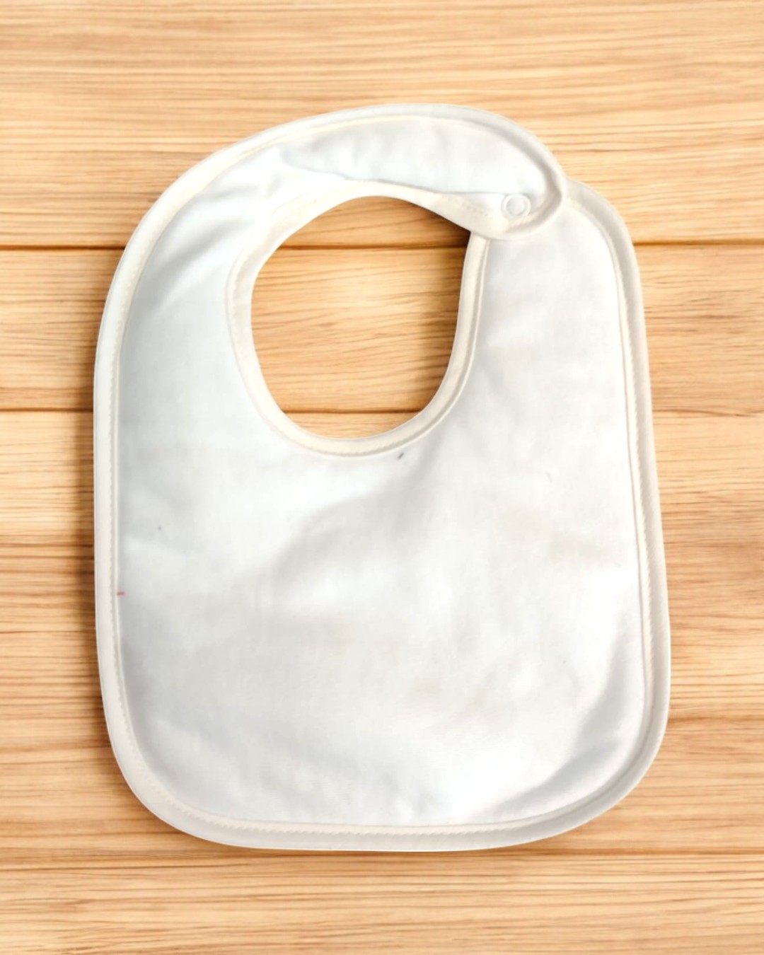 Babete branco simples em tecido macio sobre madeira clara