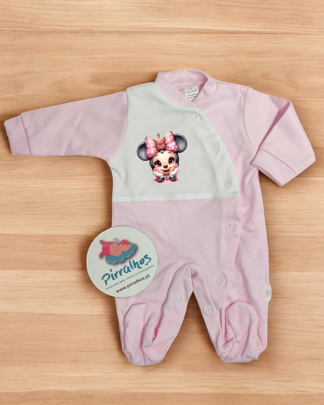 Macacão de bebé rosa e branco com estampado da Minnie Mouse e etiqueta Pirralhos.