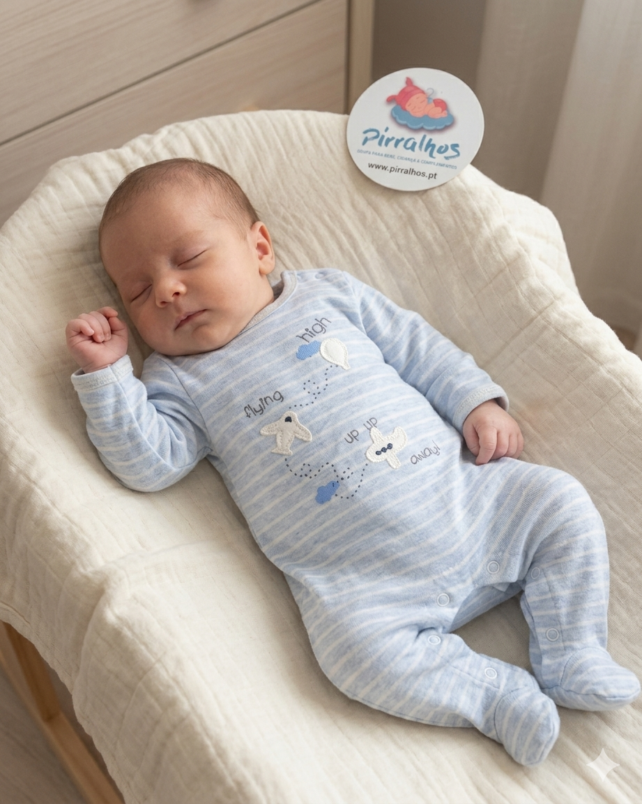 Bebé a dormir com fato de pijama azul claro às riscas e almofada creme.